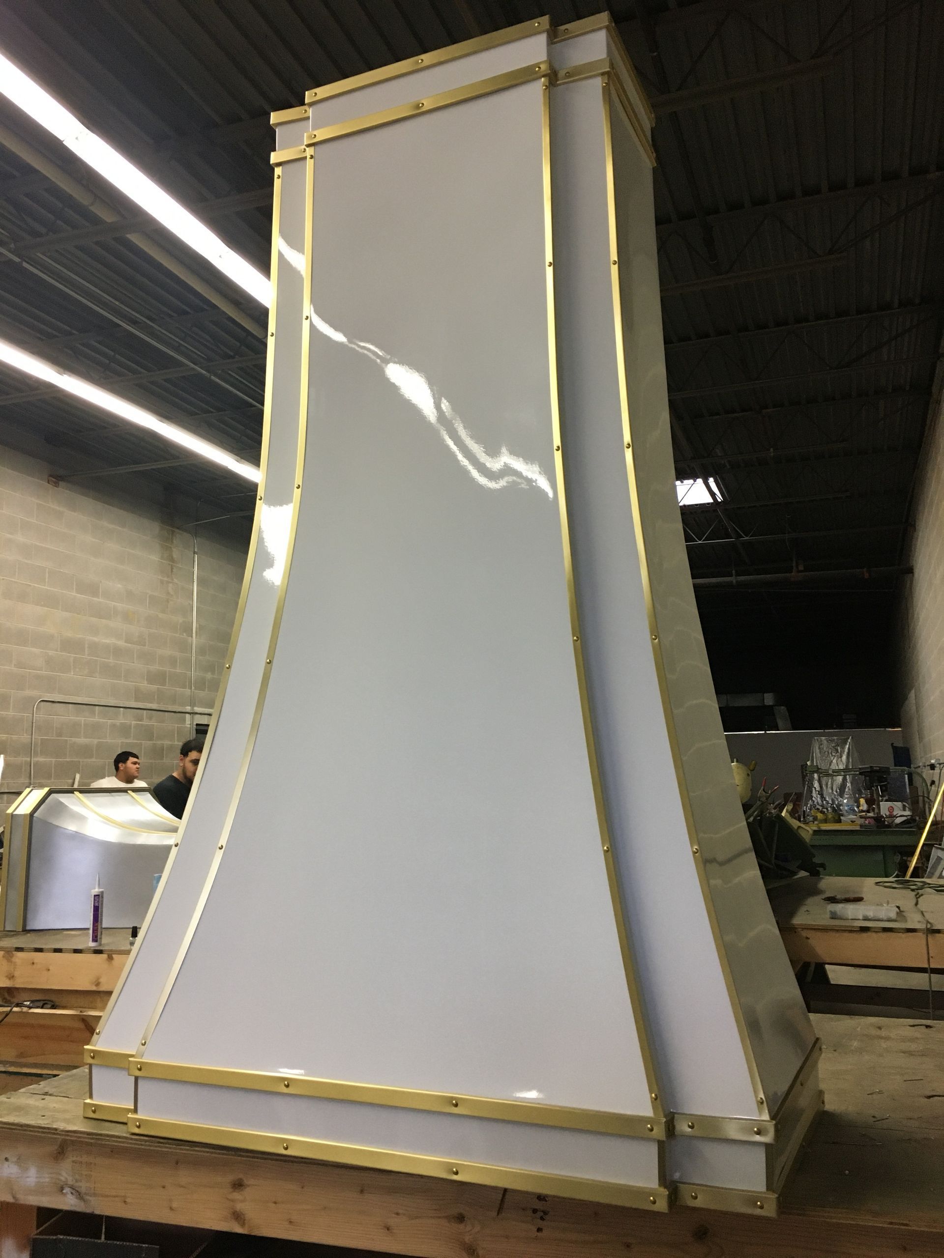 Large white tapered panel structure in a workshop, framed with masking tape and wood supports