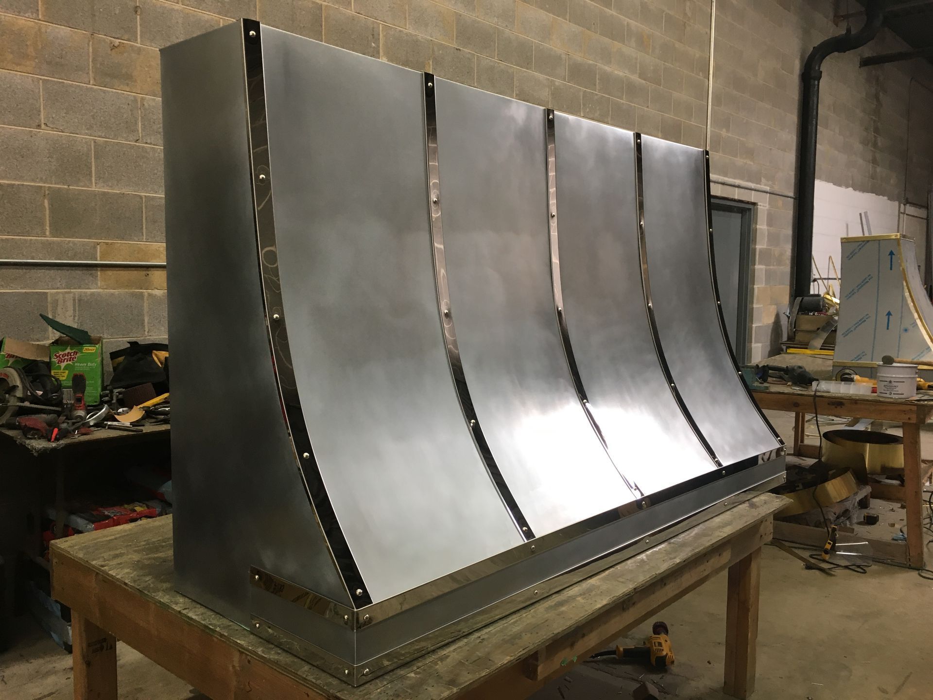 Large curved metal sheet assembly on a workbench in a workshop