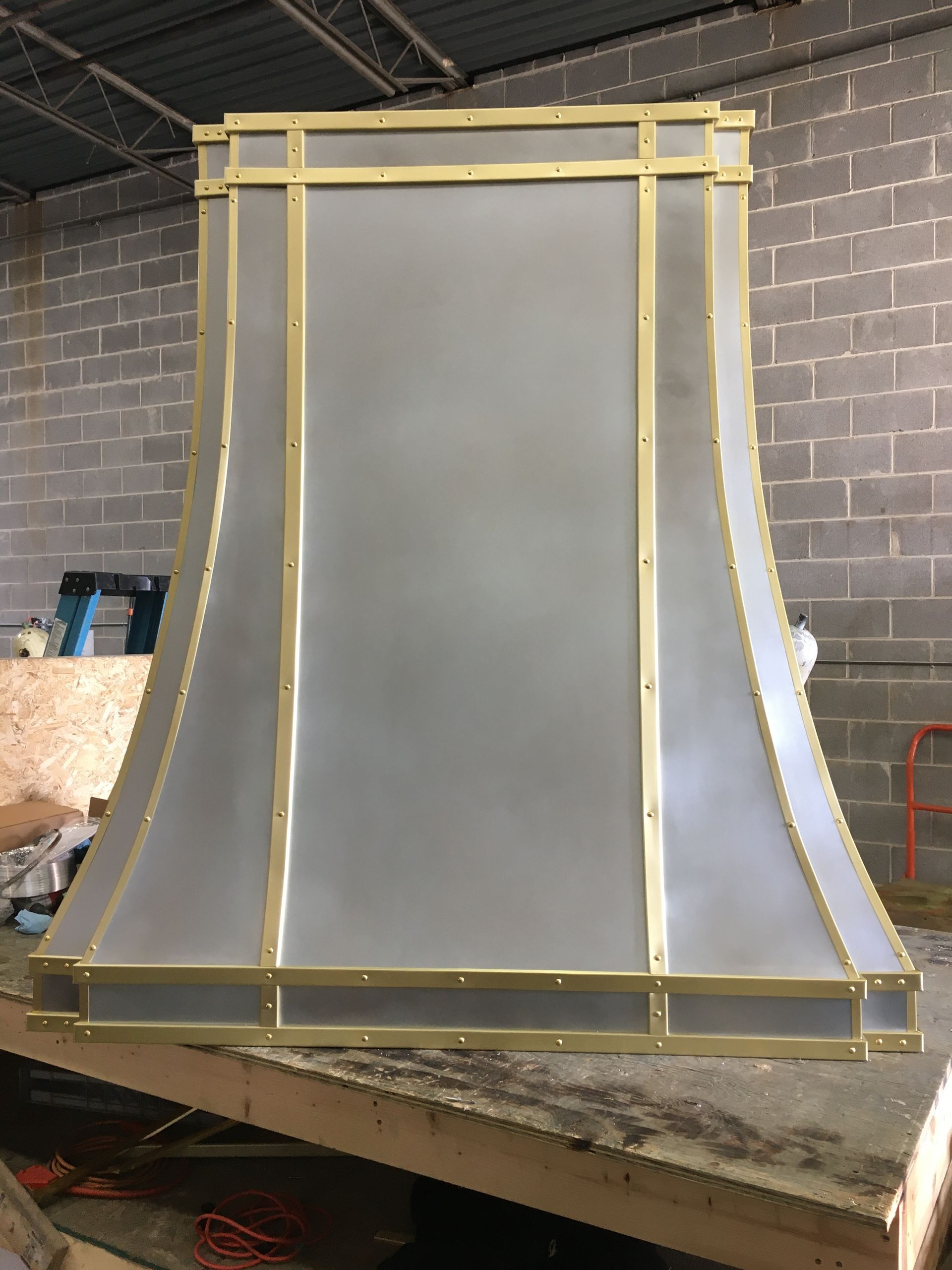 Large gray metal structure framed in yellow, standing in a workshop on a workbench.