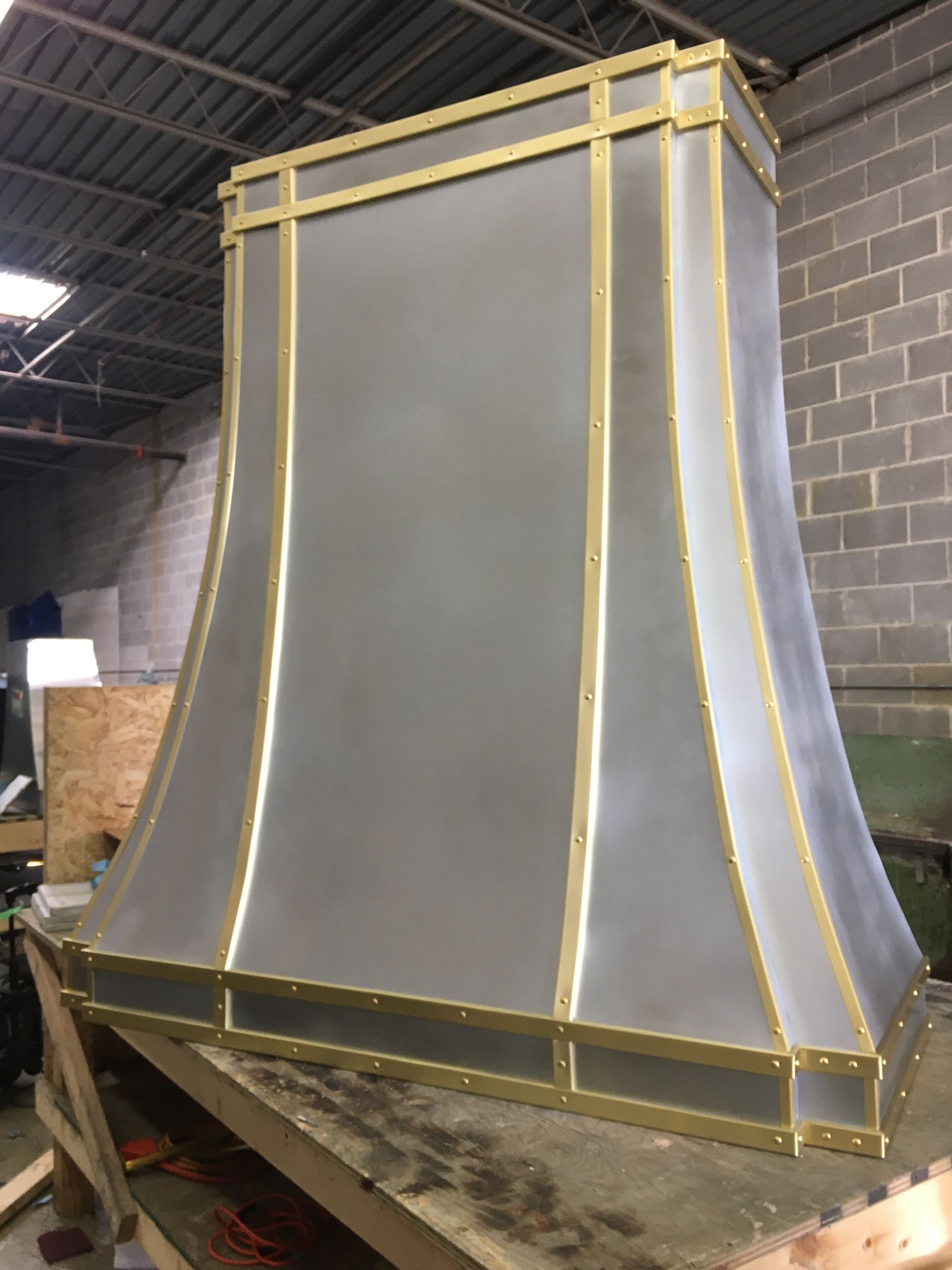 Large gray metal duct or enclosure with yellow framing in an industrial workshop