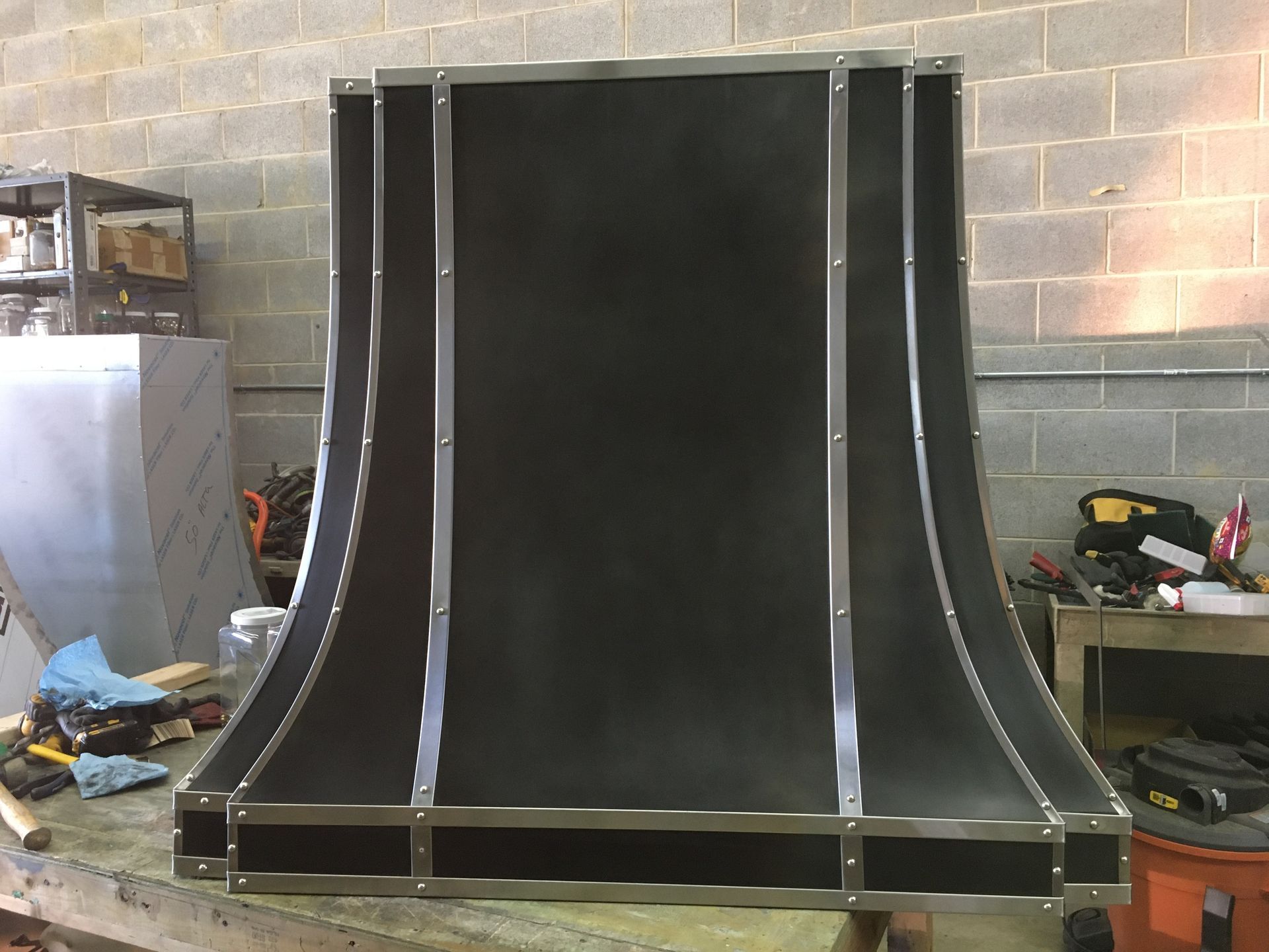 Large black curved wooden structure with silver supports in a workshop or garage setting