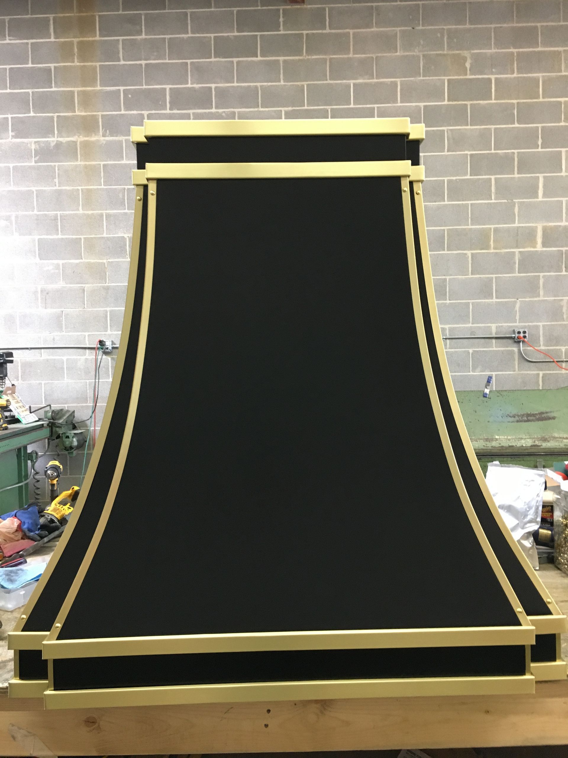 Large black curved ramp with yellow edges in a workshop or garage setting