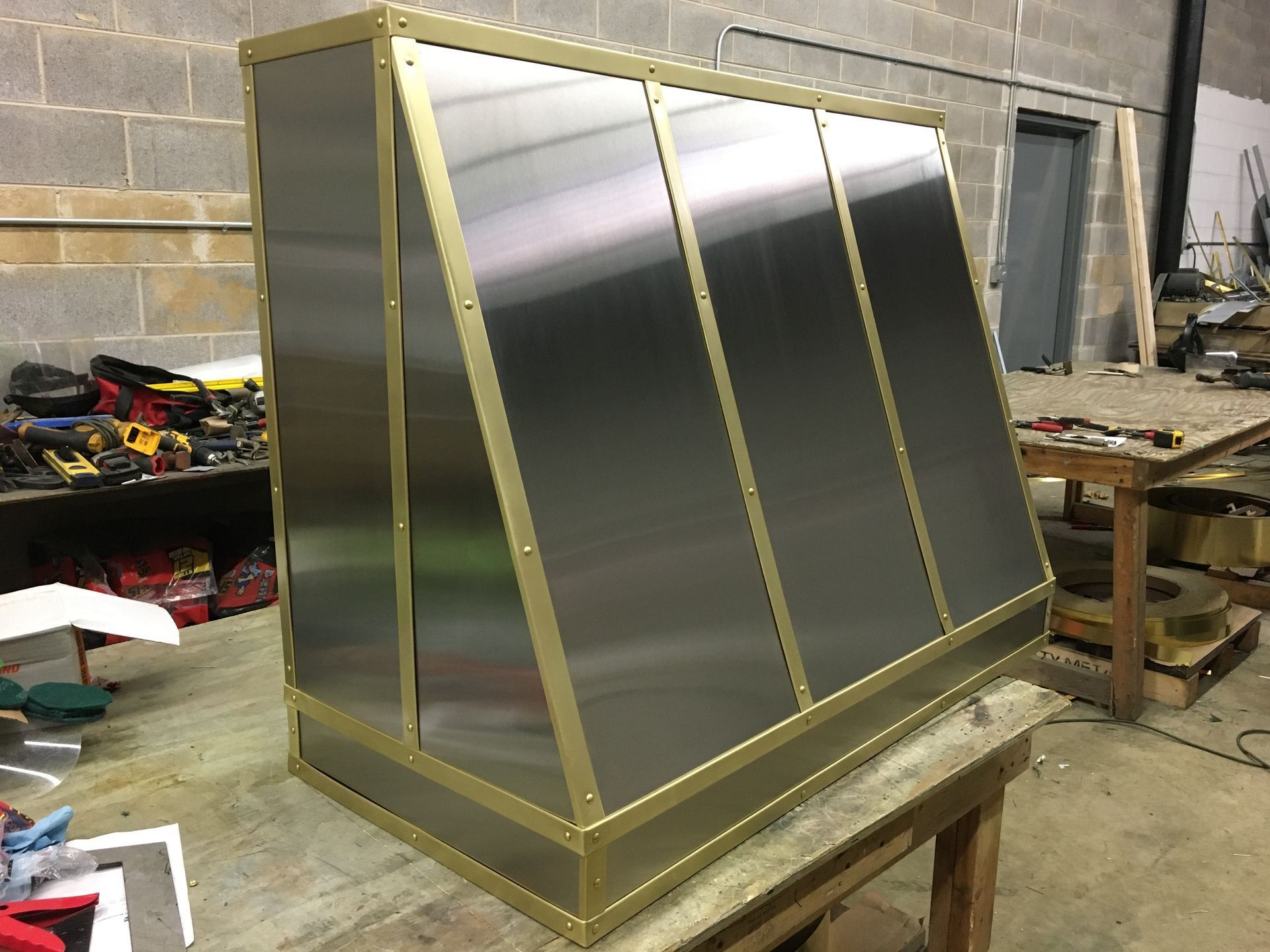 Gold-framed stainless steel cabinet on a workbench in an industrial workshop