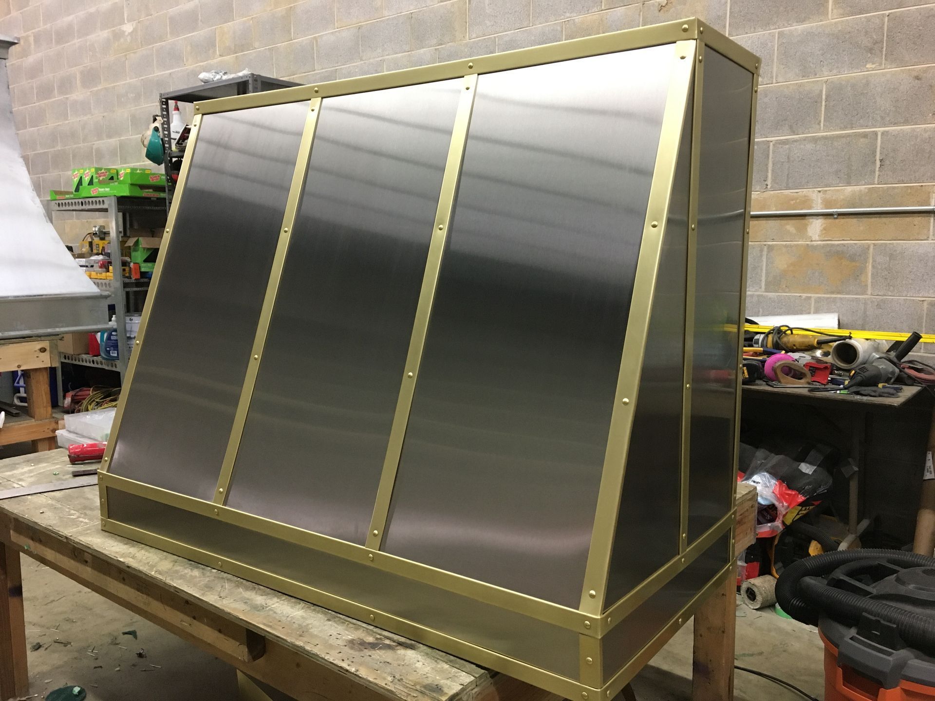 Large gold-framed mirrored display panel on a workbench in a workshop.