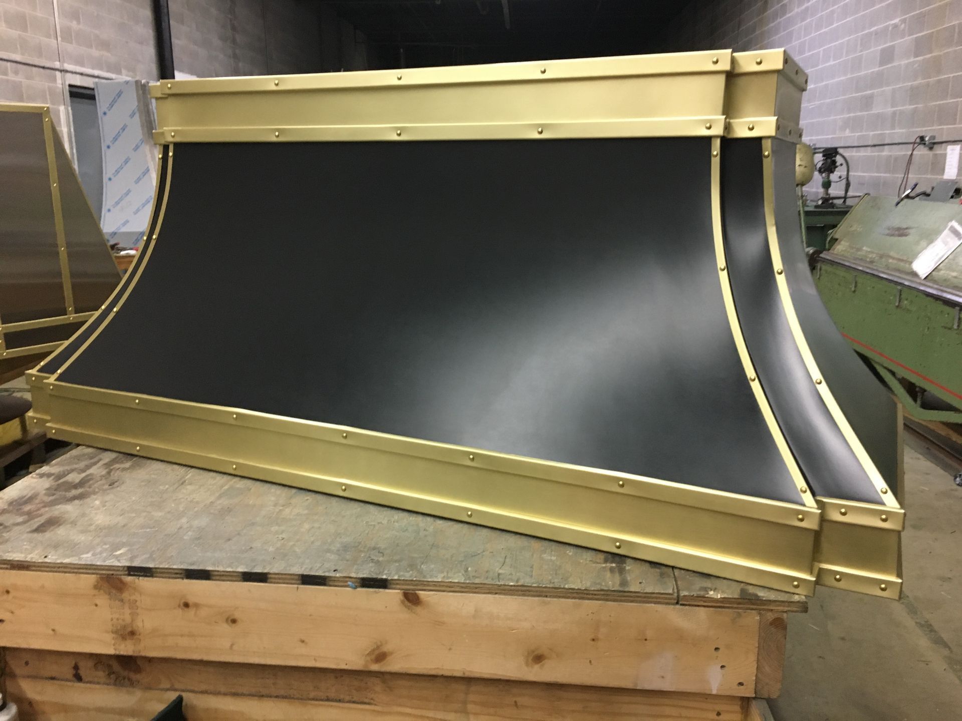 Large black industrial rubber or conveyor belt panel with yellow metal edging on a wooden pallet in a workshop