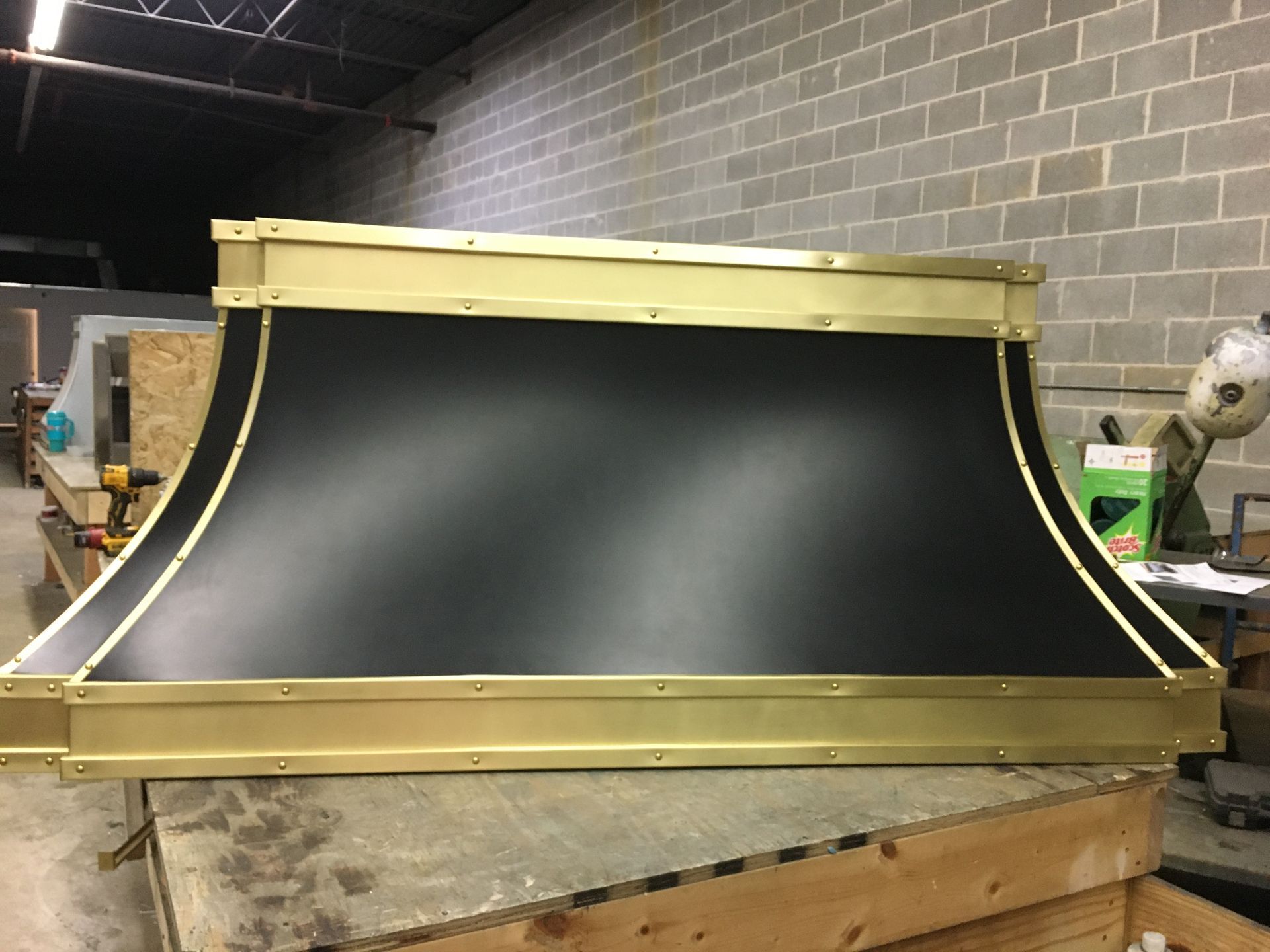 Gold-trimmed black curved industrial panel on a workbench in a workshop