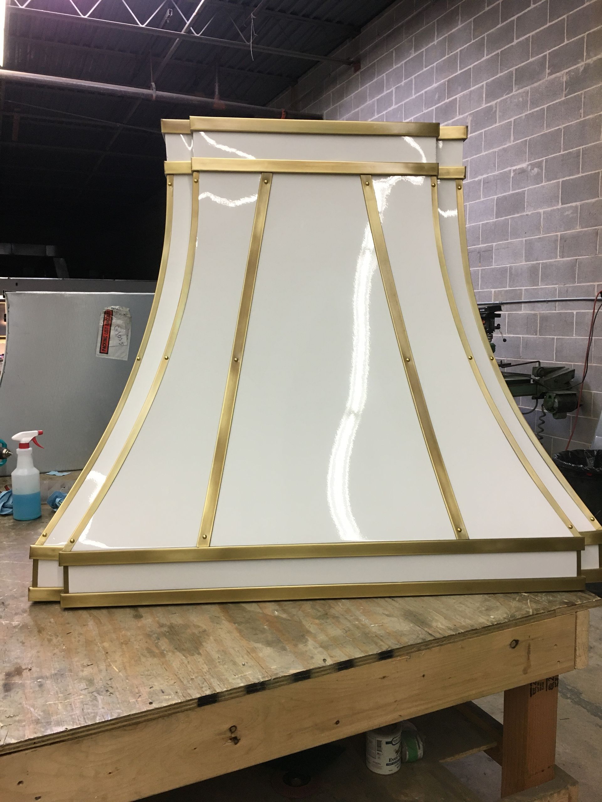 White lampshade frame with gold trim on a workbench in a workshop