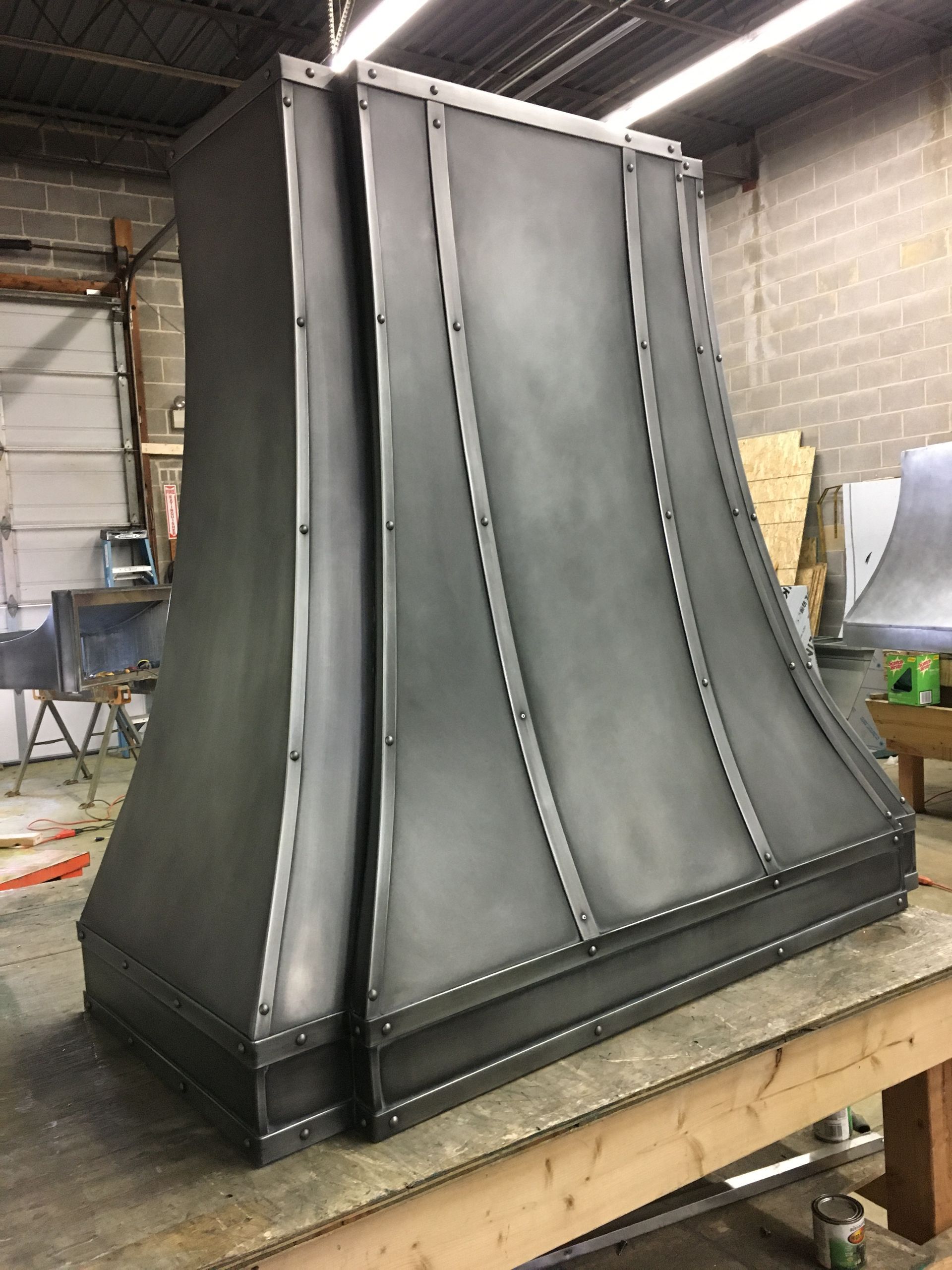 Large gray metal duct or vent hood standing on a workbench in a workshop
