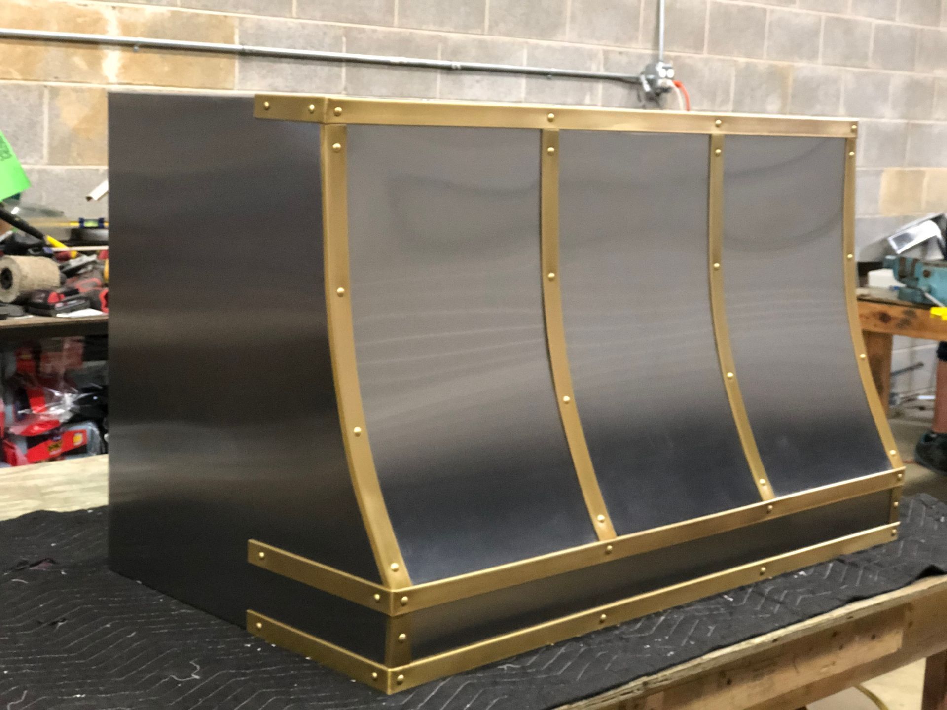 Bronze-and-black curved metal display case on a workshop table