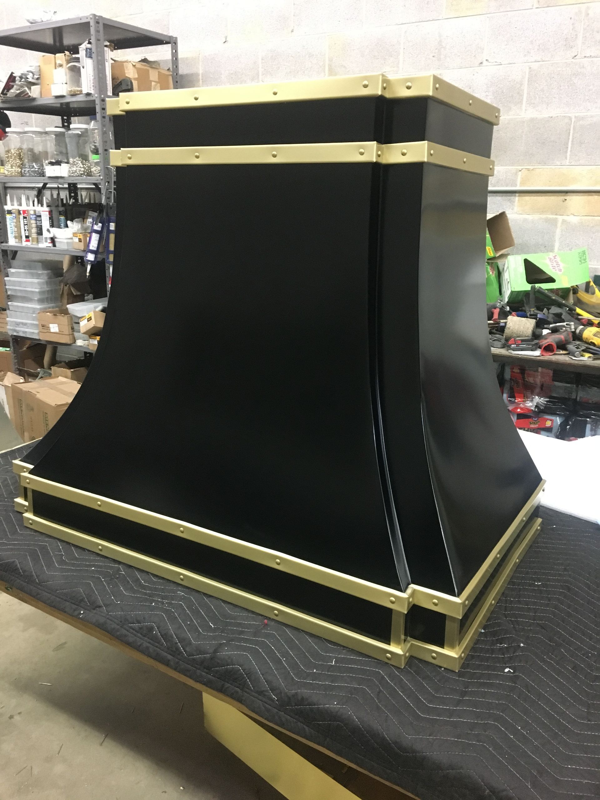 Black and gold decorative box or enclosure on a workbench in a workshop setting