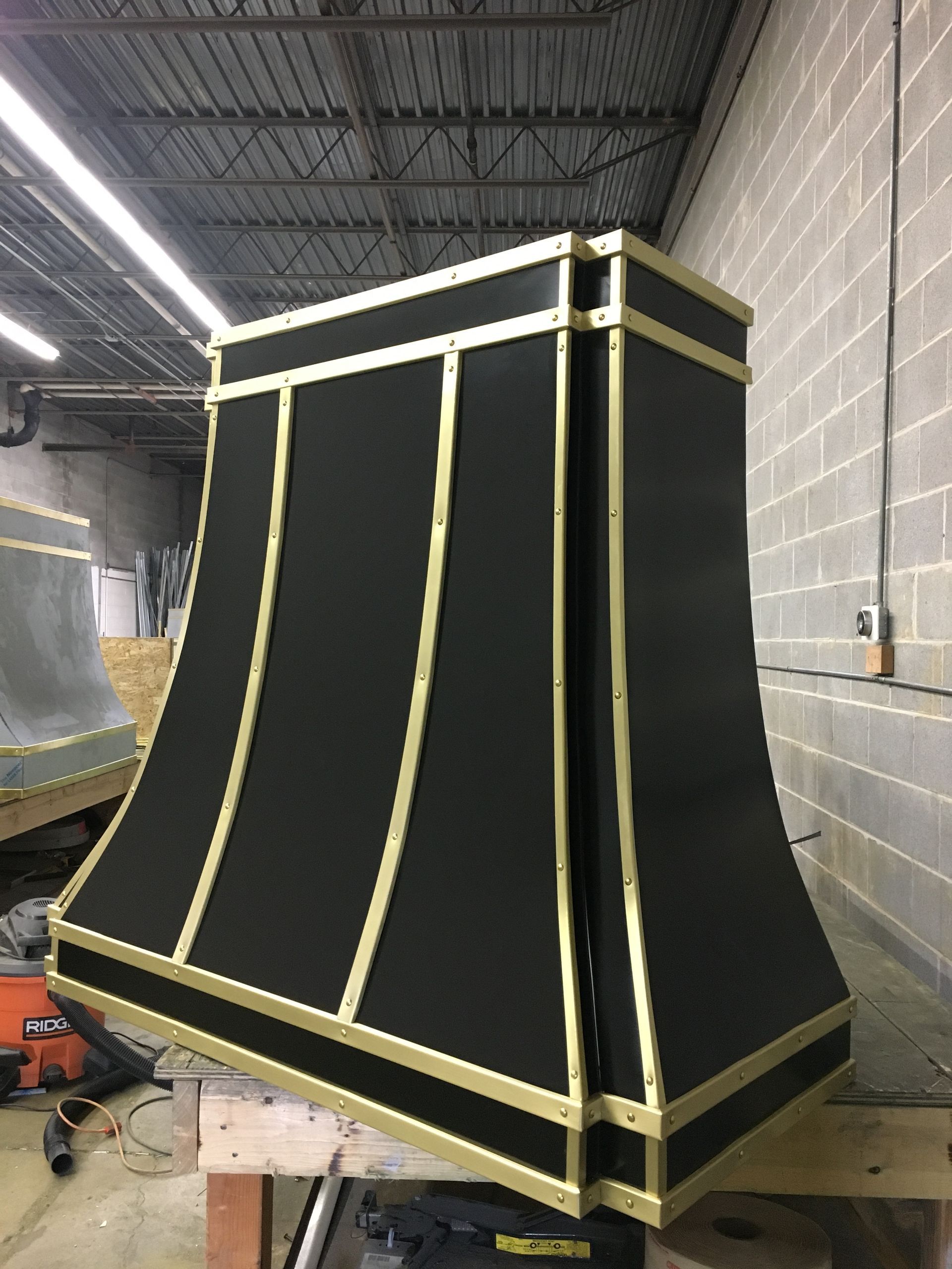 Large black-and-yellow painted industrial machine housing in a workshop against a cinderblock wall