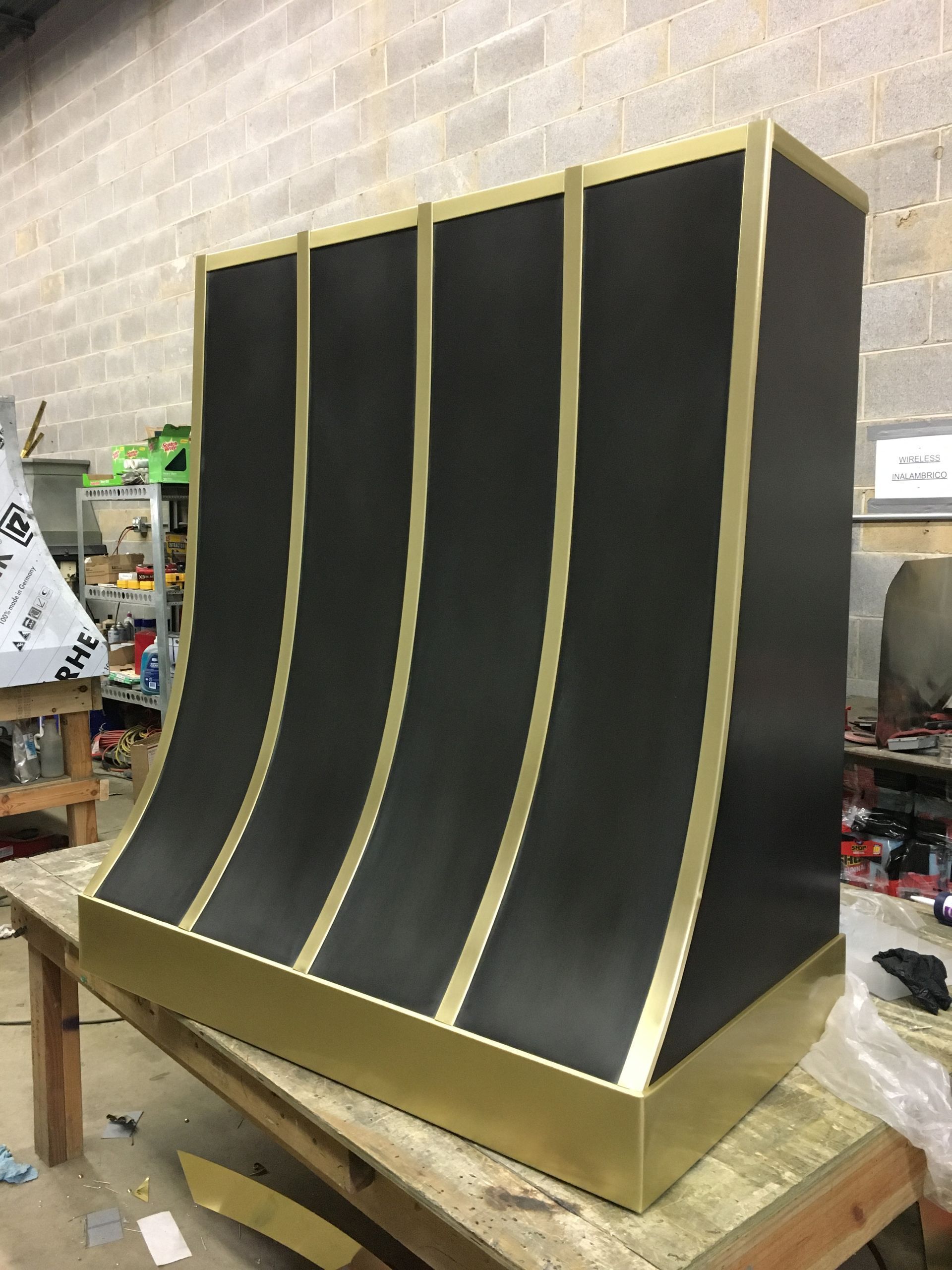 Black curved display with gold trim on a workbench in a workshop