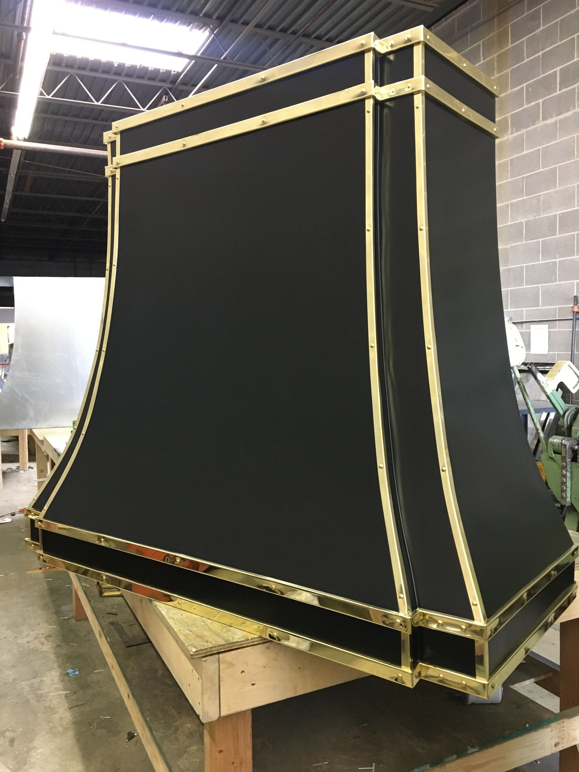 Large black fabric-covered structure with gold trim, standing on a wooden platform in a workshop.