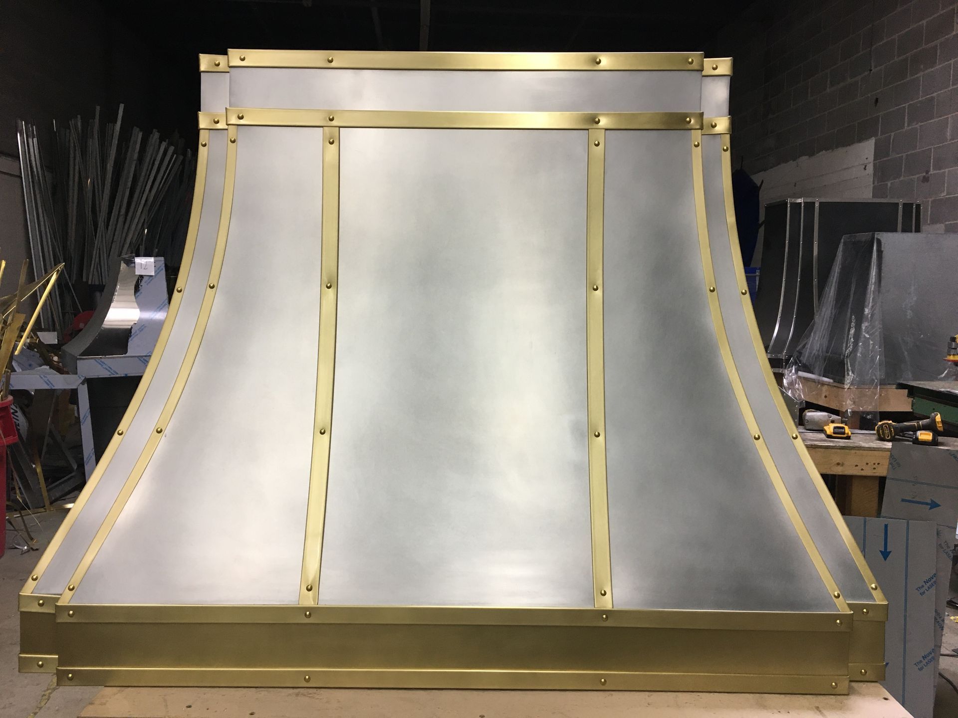 Metal roof panel assembly with gold trim in a workshop, shown front-facing on a workbench.