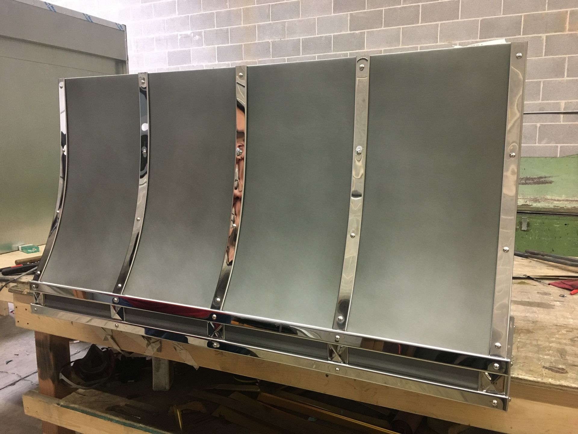 Curved metal panels mounted on a wooden frame in an industrial workshop