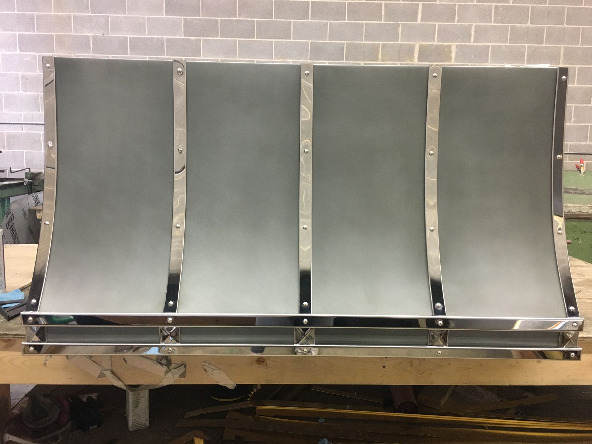 Four gray metal panels mounted on a pallet in a workshop against a brick wall