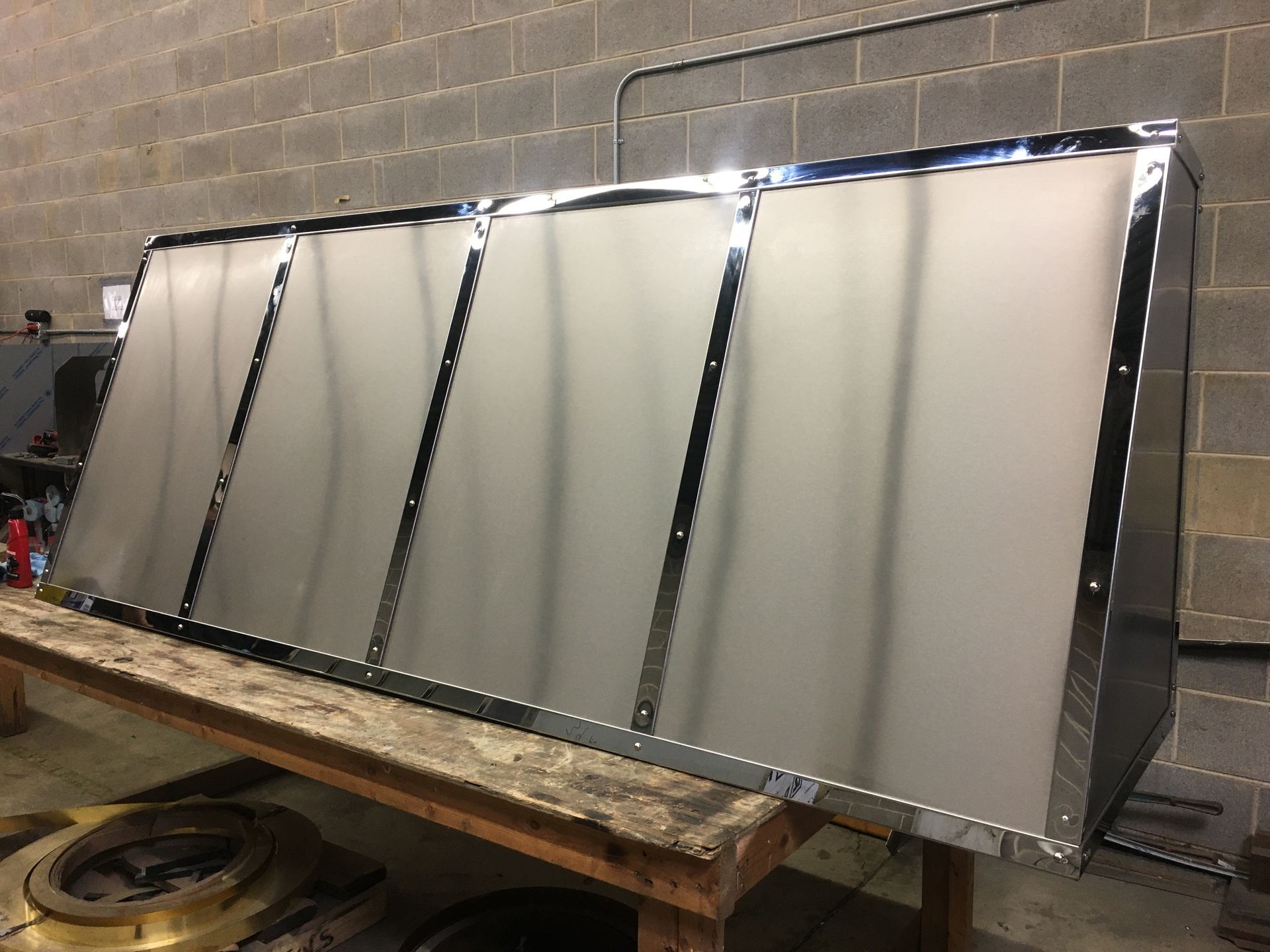 Large silver metal enclosure with vertical black supports in an industrial workshop