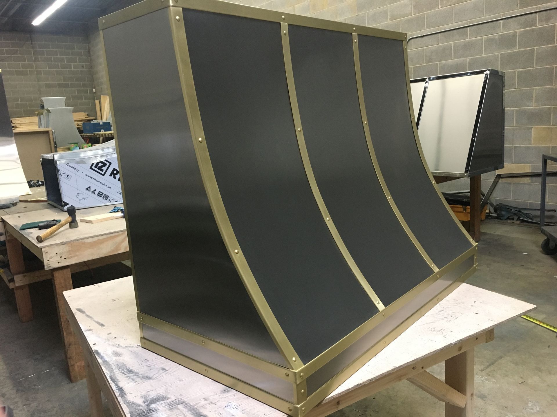 Black curved panel with gold trim on a workbench in a workshop