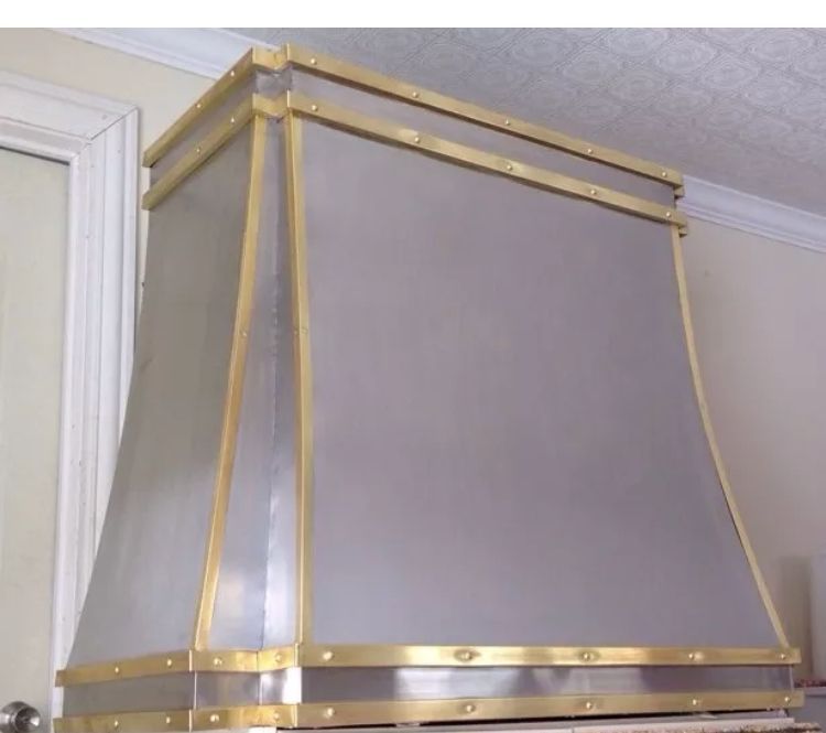 Brass-framed wall-mounted hood with gray fabric panels in a room corner