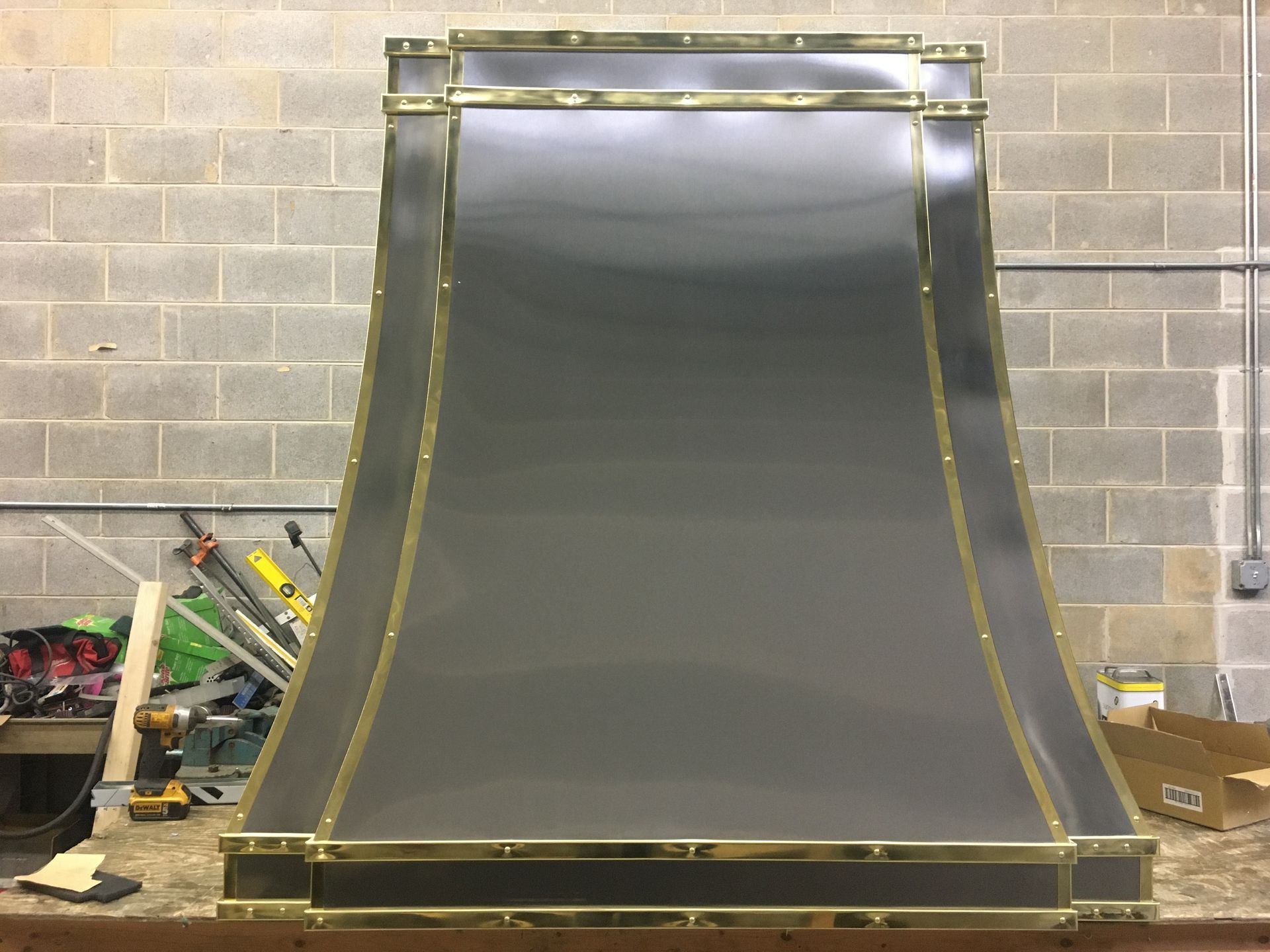 Large dark gray curved ramp with yellow rails, set against a cinderblock wall in a workshop.