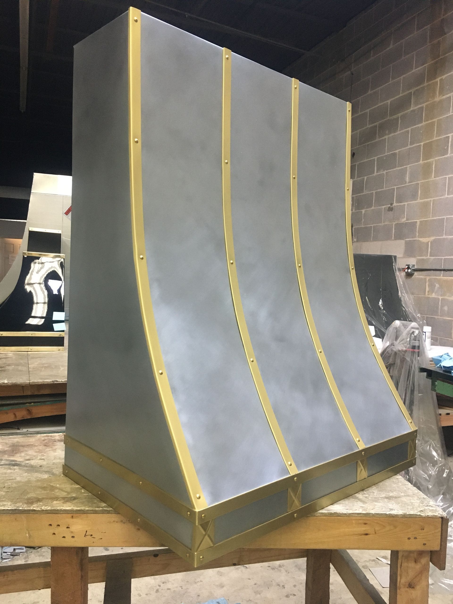 Gray curved metal panel with yellow trim on a workbench in a workshop