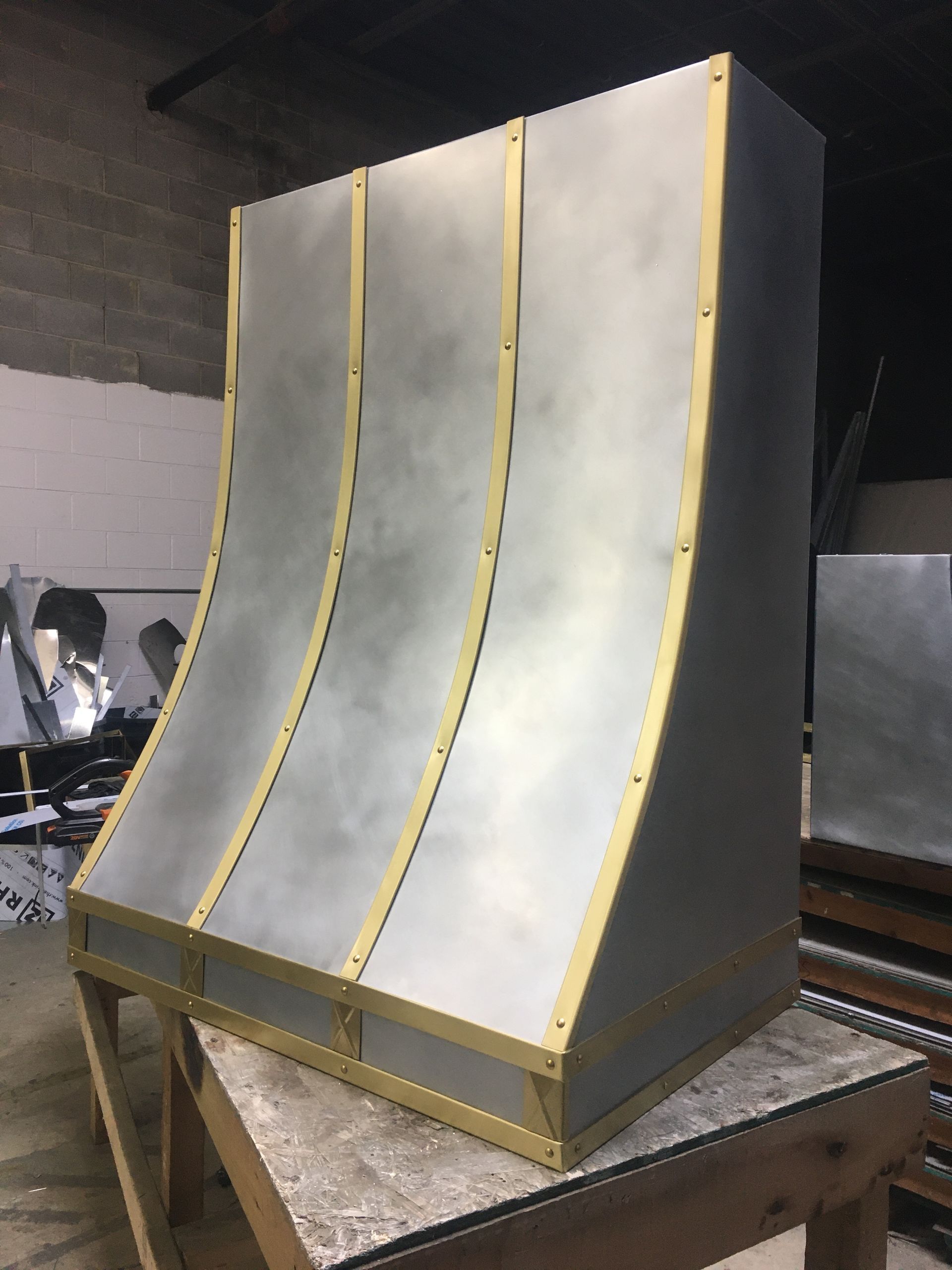 Large gray curved panel prototype with yellow seams on a wooden table in a workshop