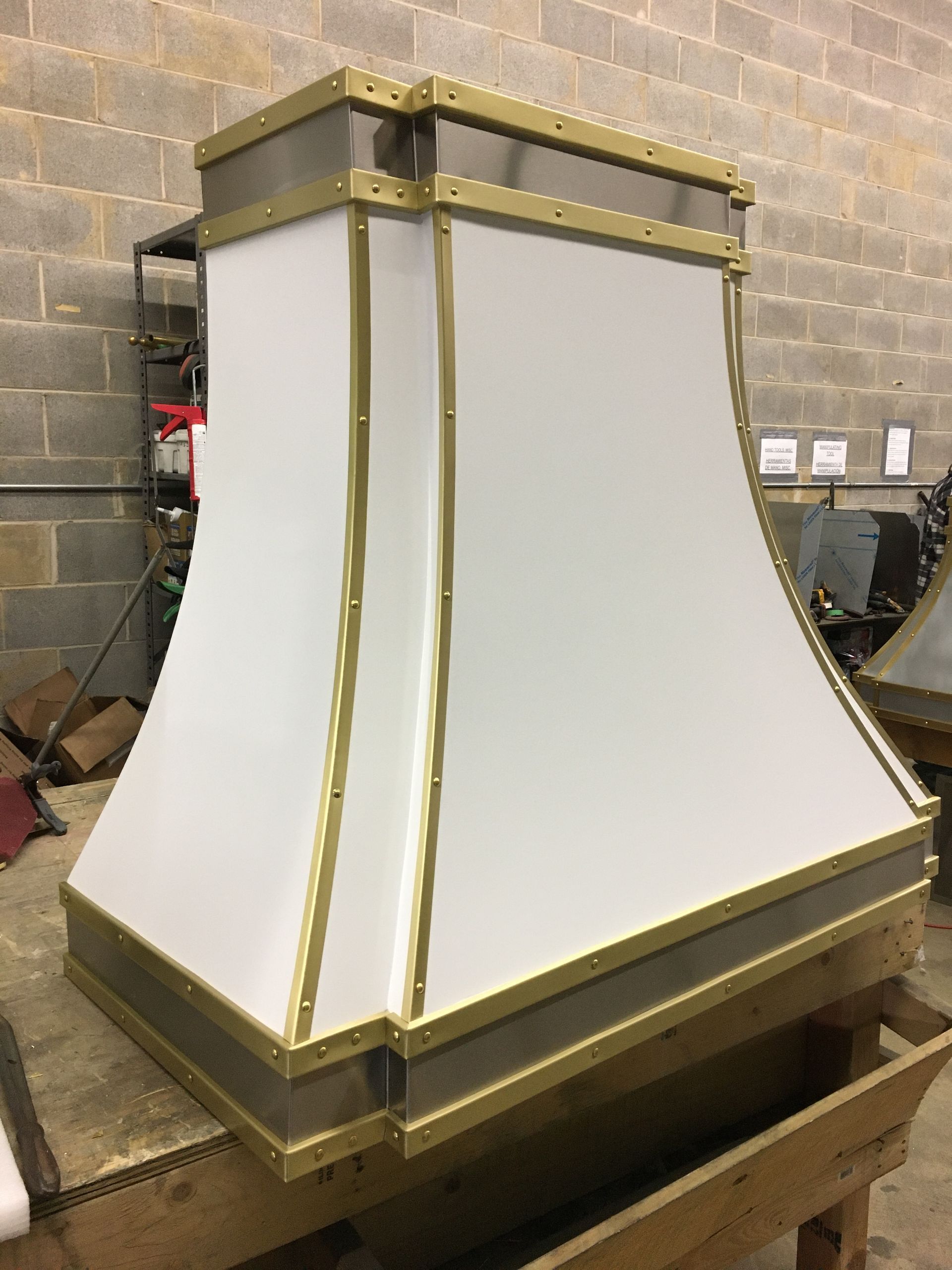 White pleated lampshade with gold trim sitting on a workbench in a workshop