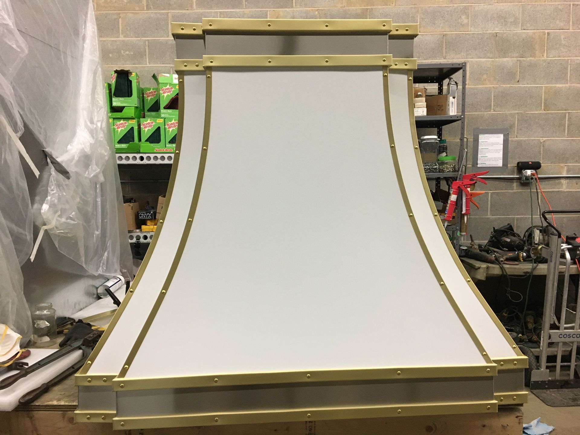 Large white curved architectural panel with gold trim in a workshop or storage area