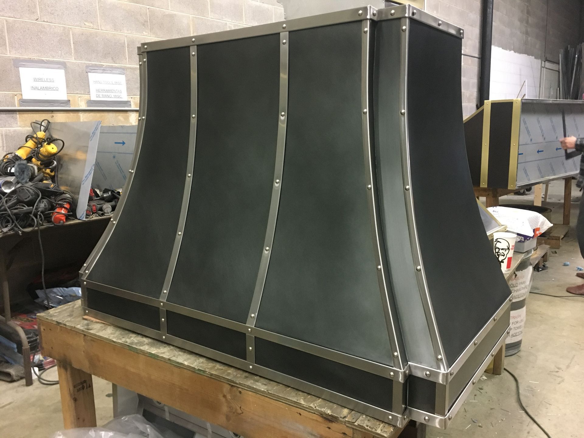 Large black metal duct or enclosure on a wooden workbench in a workshop