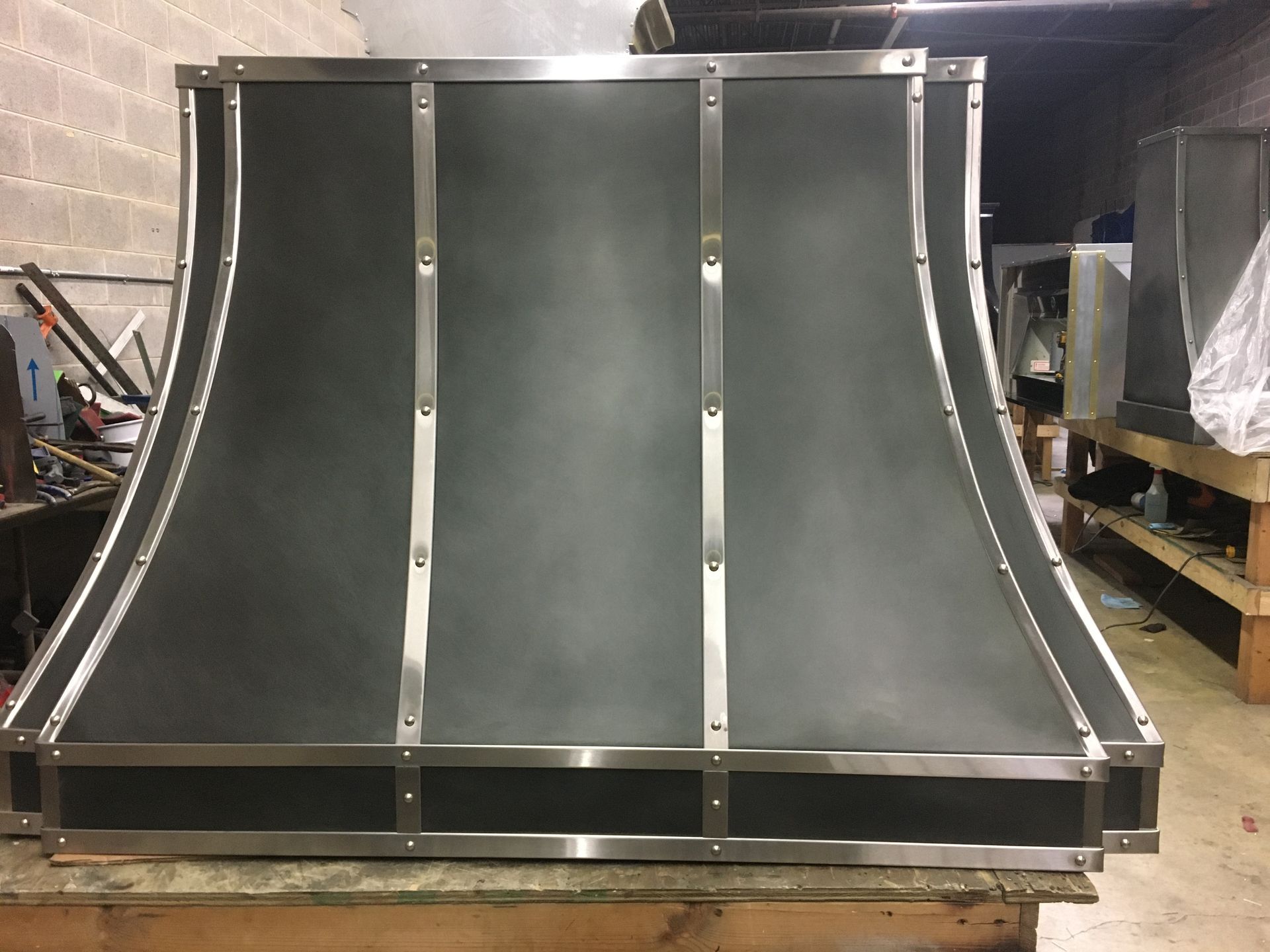 Curved black metal ramp or half-pipe with silver frame in a workshop or warehouse