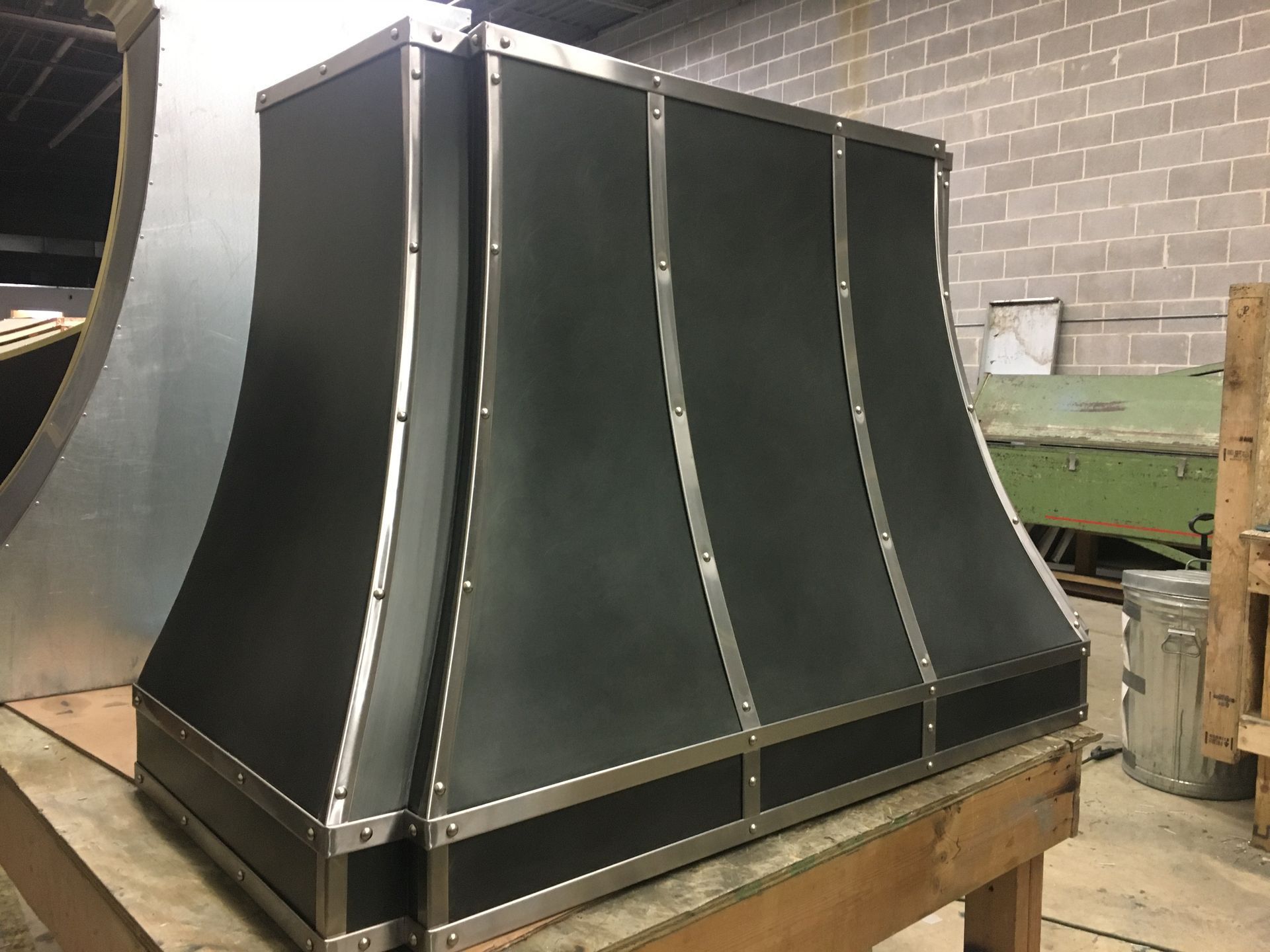 Black metal ventilation duct on a wooden pallet in a workshop