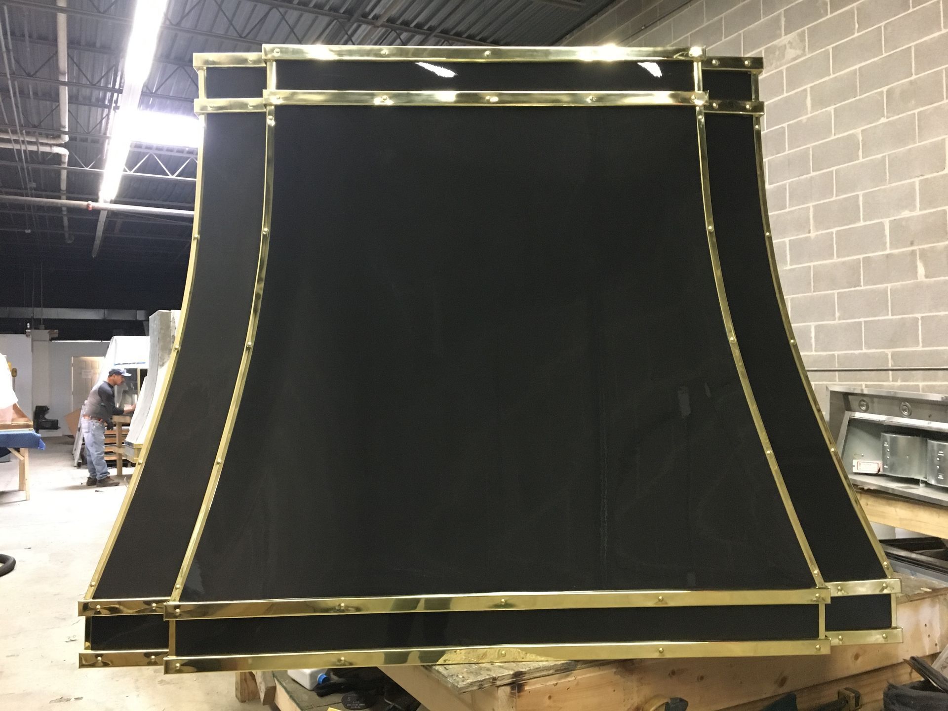Large black curved display panel with gold frame in an industrial workshop