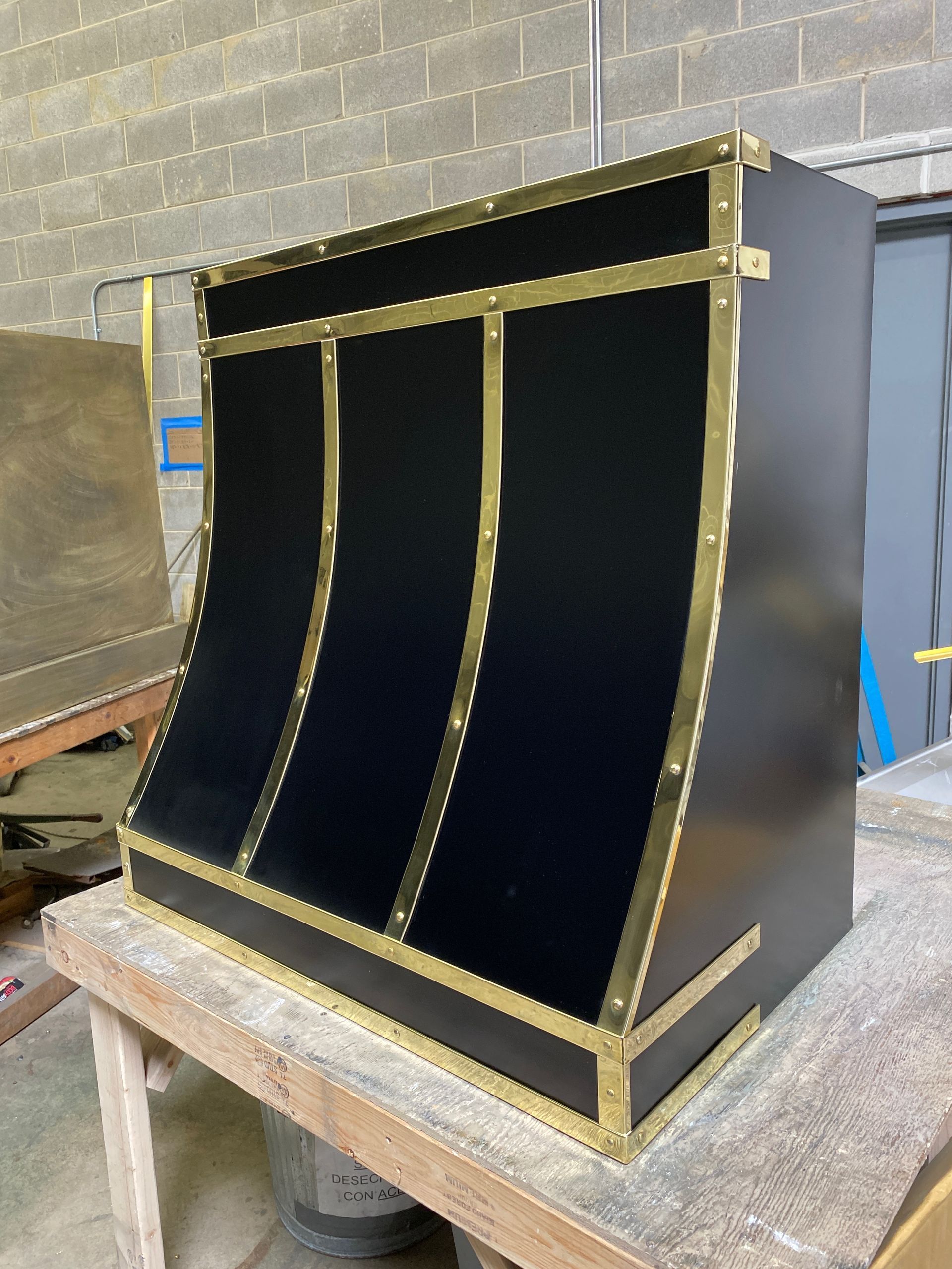 Black and gold curved cabinet or panel on a workbench in a workshop setting