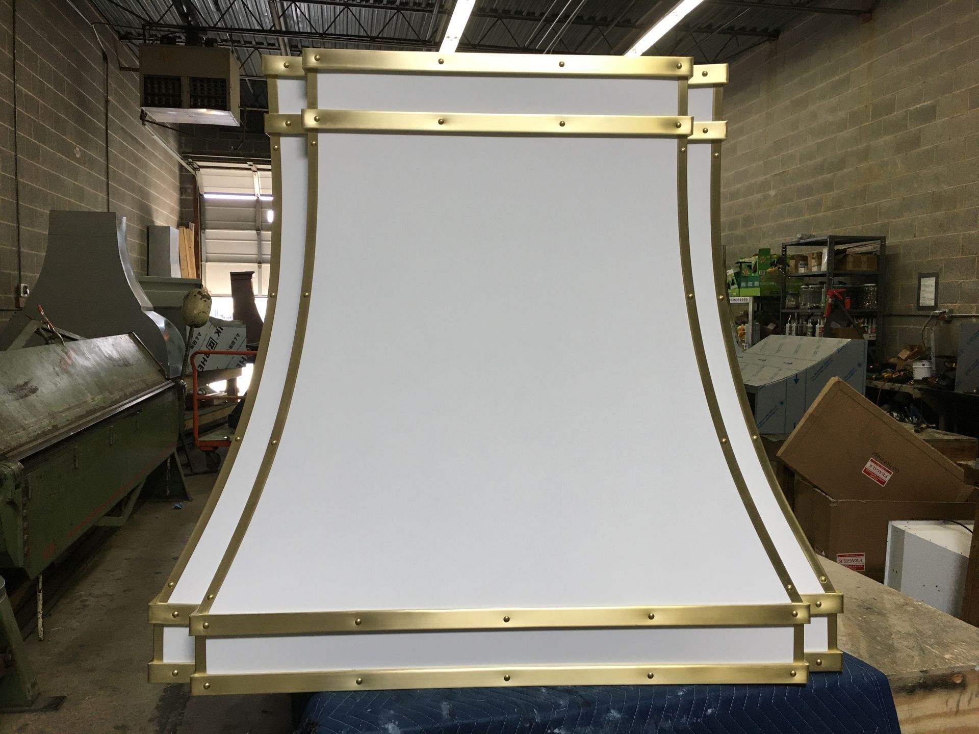 Large white fabric panel with gold frame in a workshop or industrial warehouse