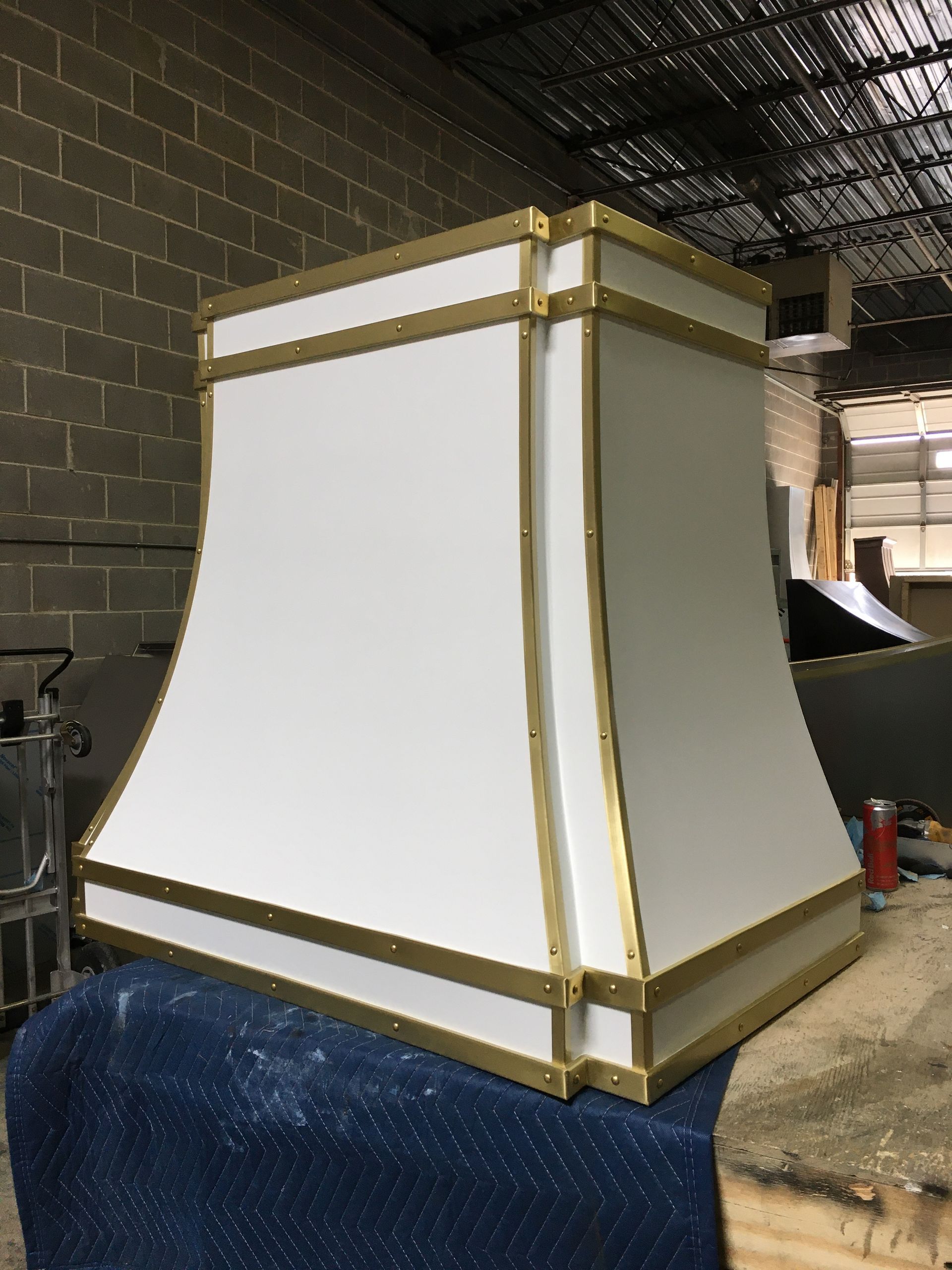 White lampshade with gold trim resting on a blue chair in a workshop-like space