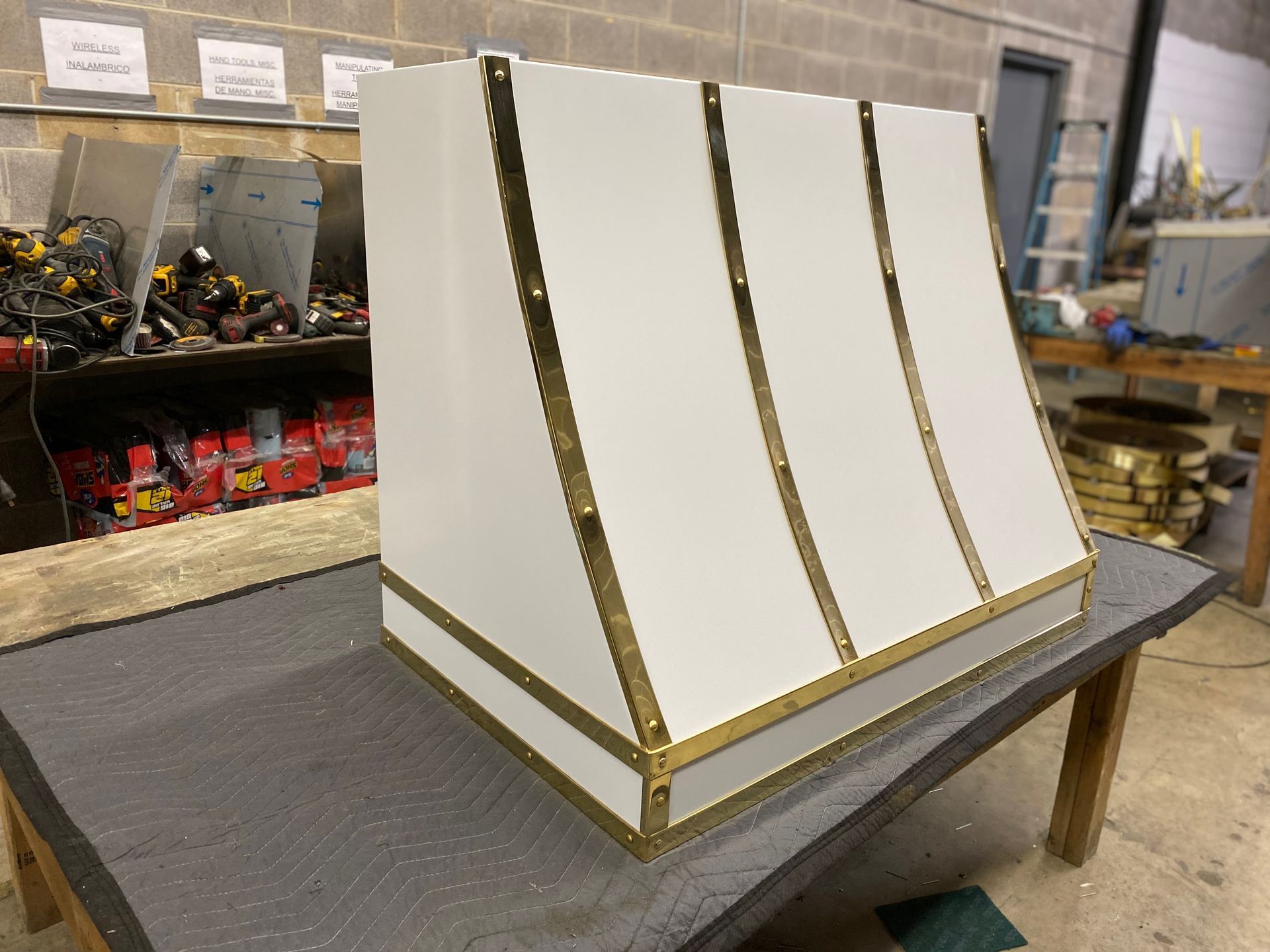 White wedge-shaped display model with gold trim on a worktable in a workshop.