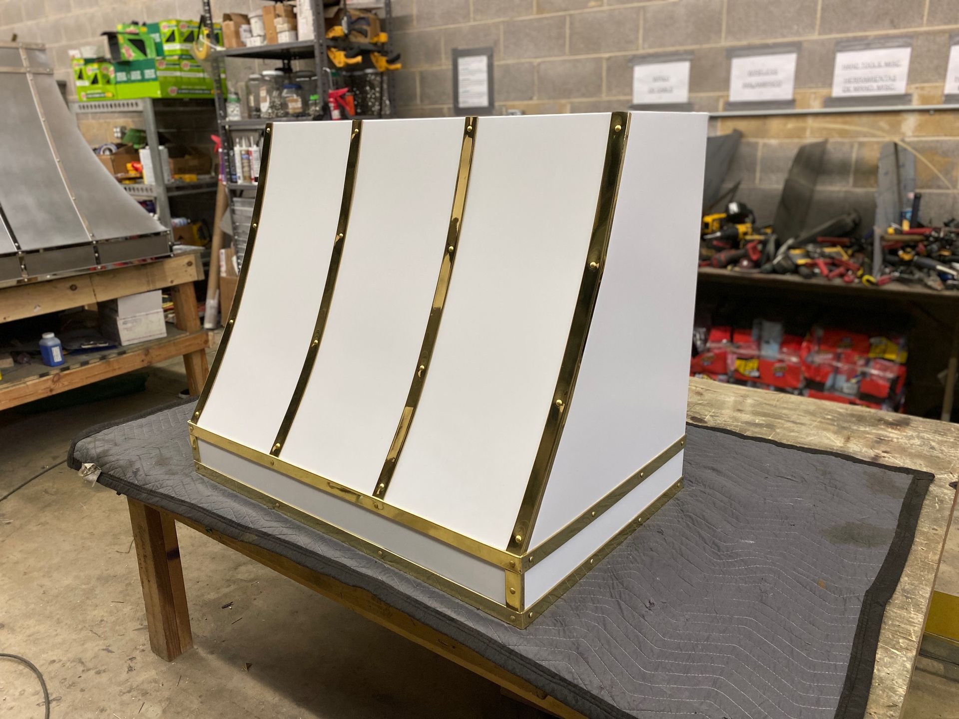 White slanted display stand with gold trim on a workbench in a workshop.