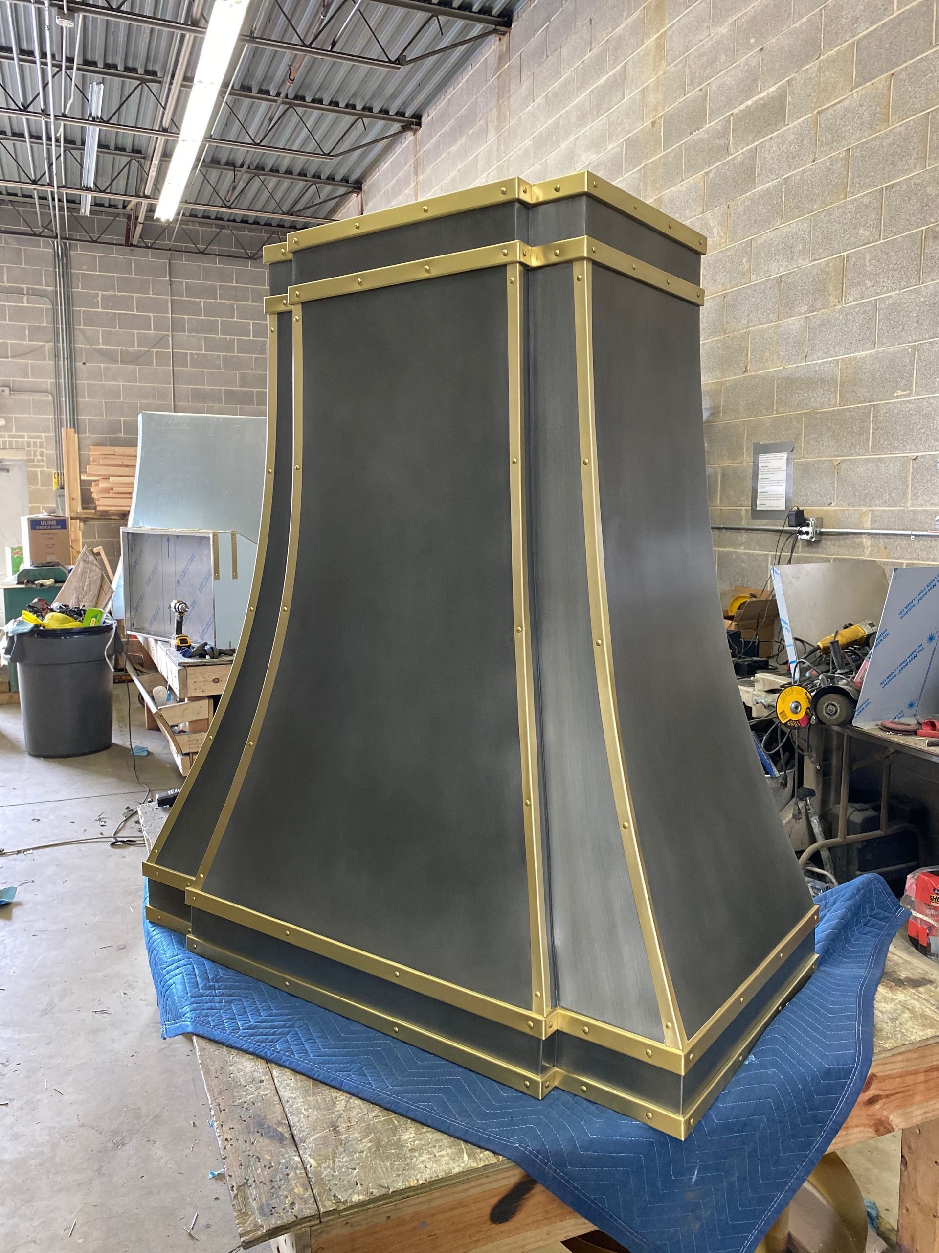 Black-and-gold decorative column or pedestal in a workshop, standing on a blue tarp