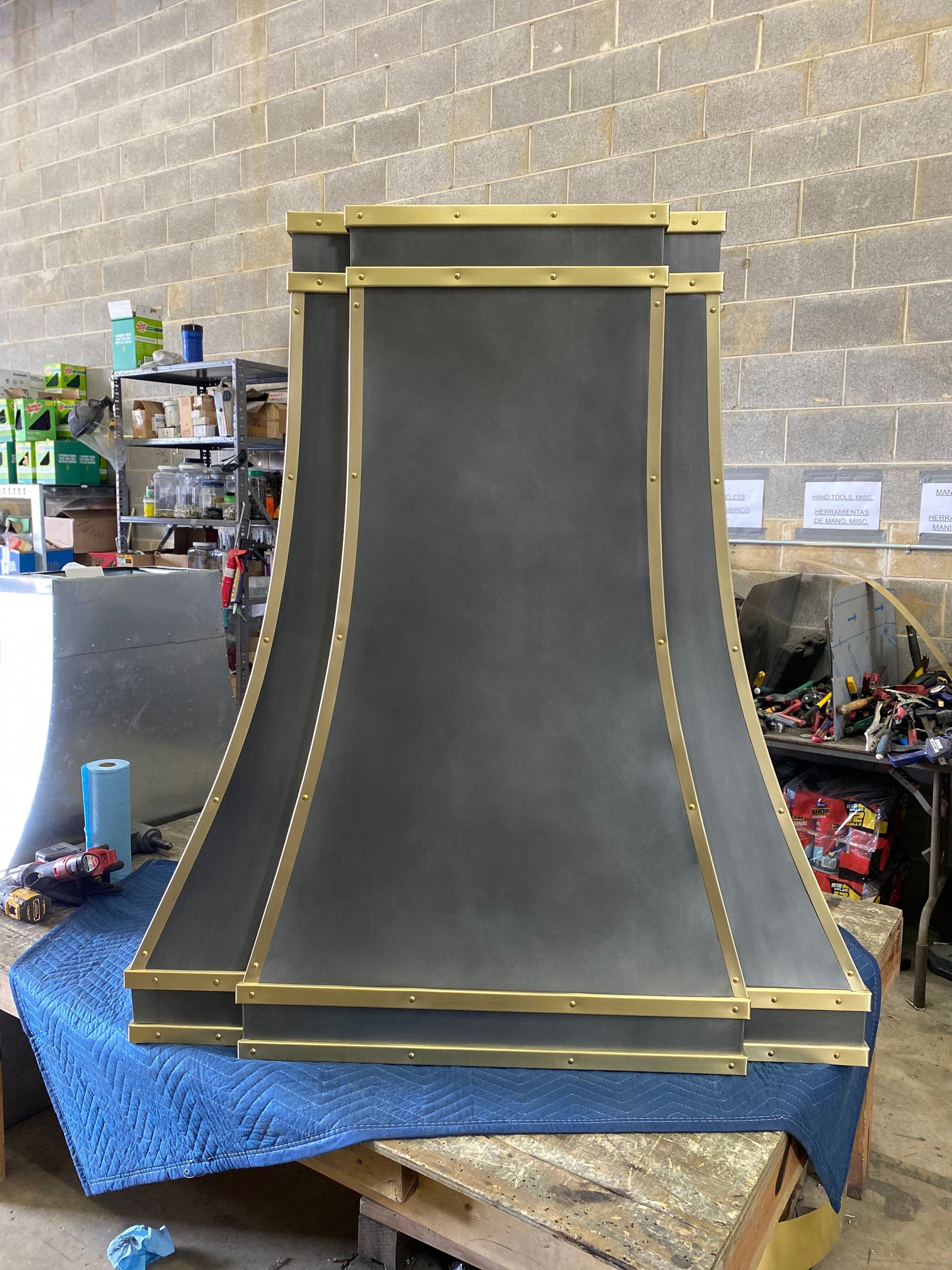 Large black-and-gold decorative panel standing in a workshop, with a flared base and top trim.