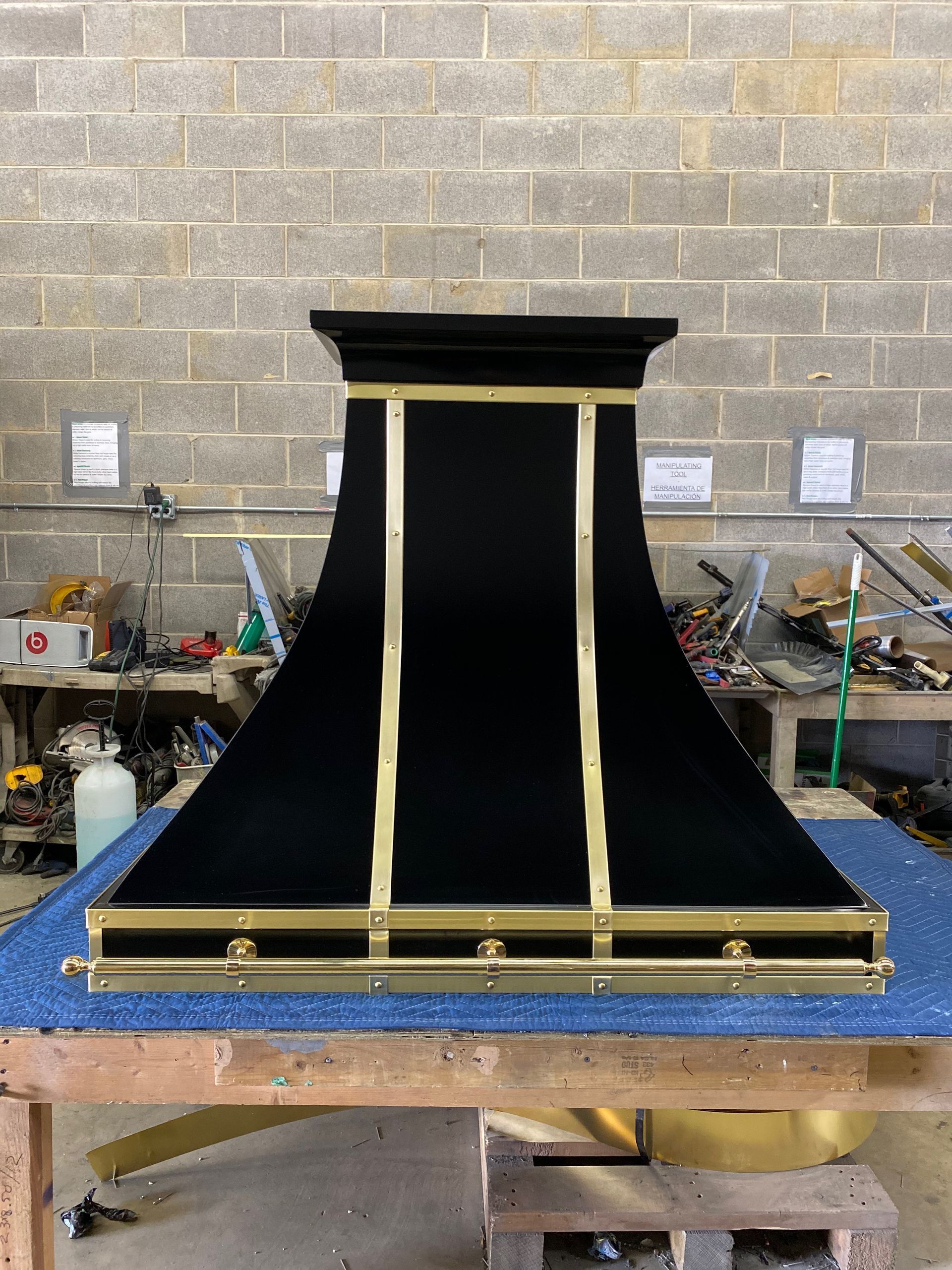 Black-and-gold model of a ship’s stern or bow on a worktable in a workshop