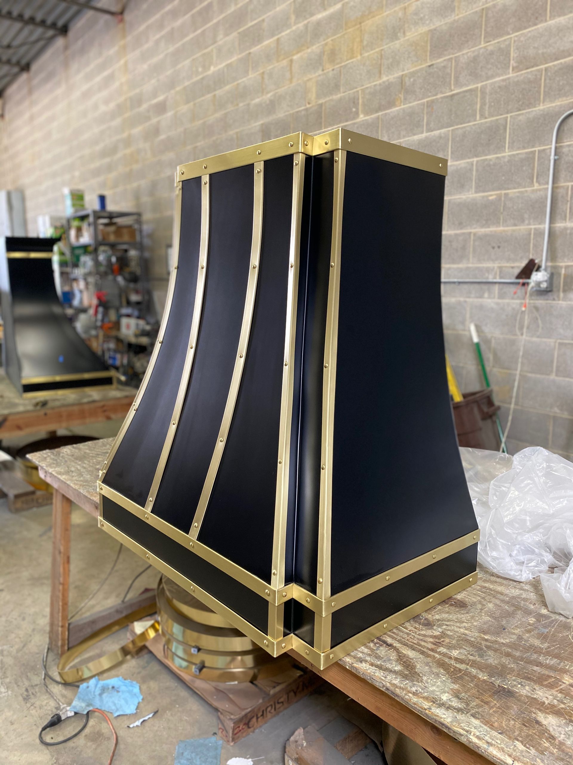Black and gold curved decorative panel in a workshop, resting on a workbench