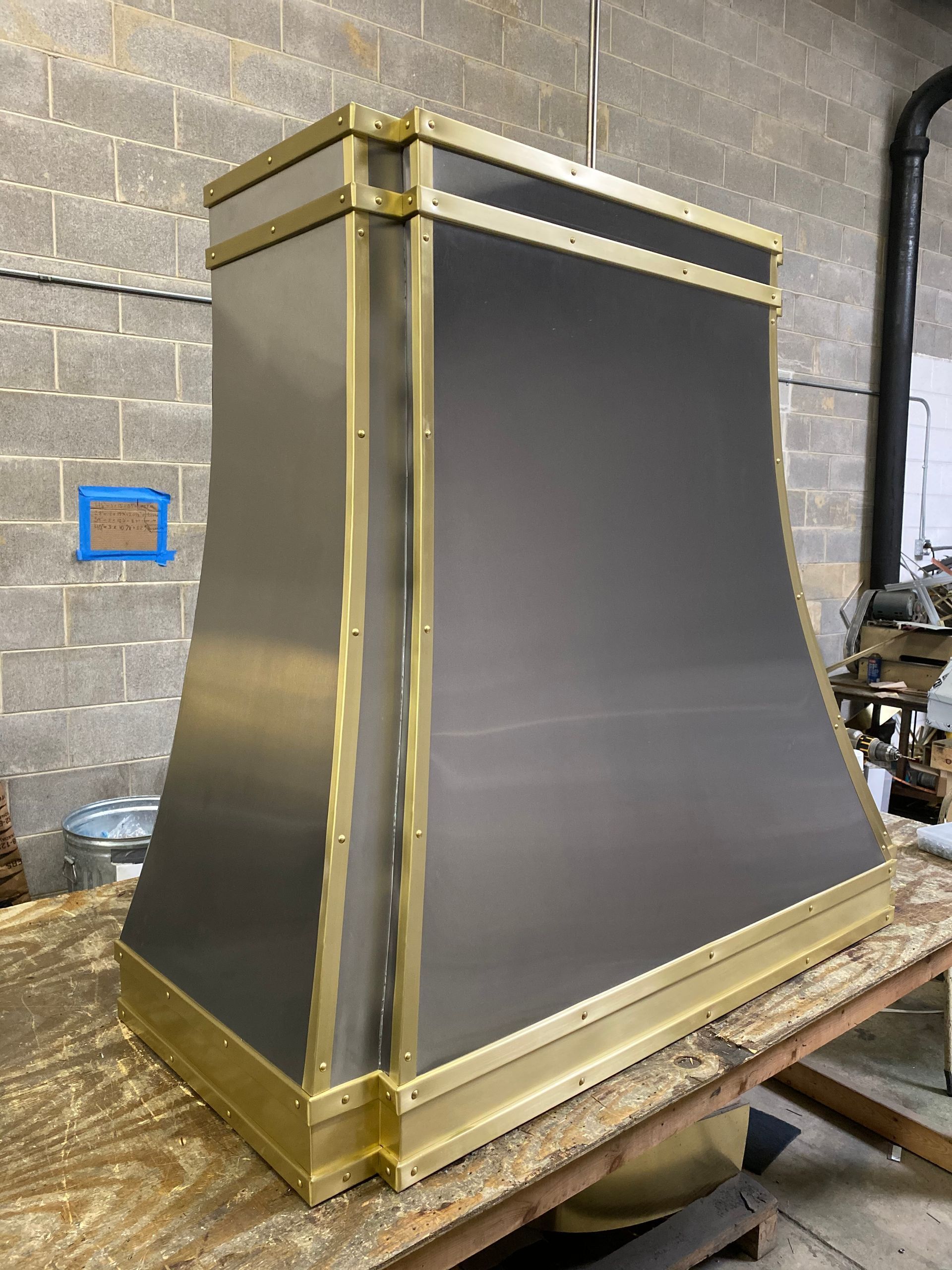 Large black-and-gold industrial panel or enclosure on a workbench in a workshop