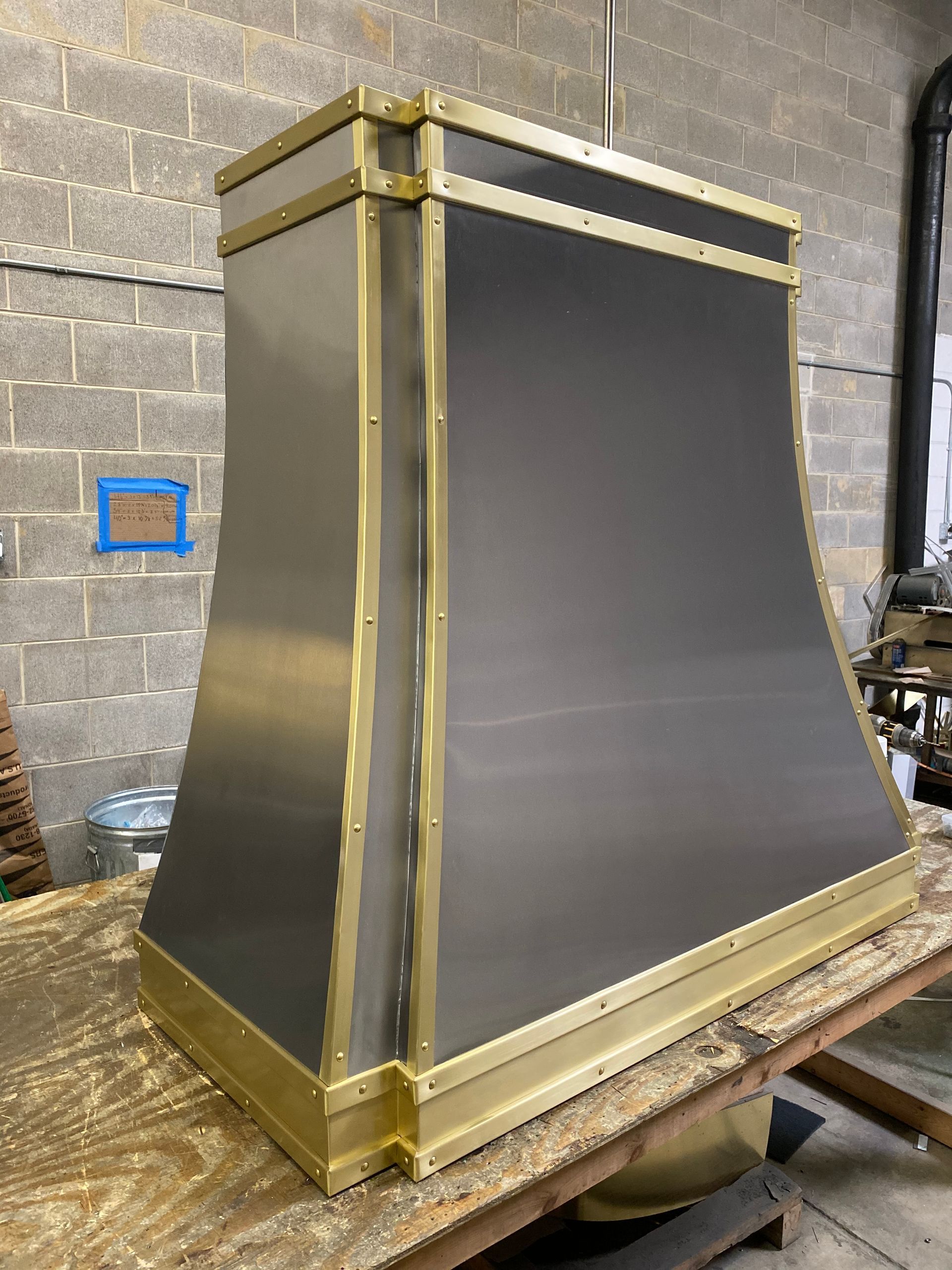 Large gold-trimmed black metal structure leaning on a workbench in a workshop