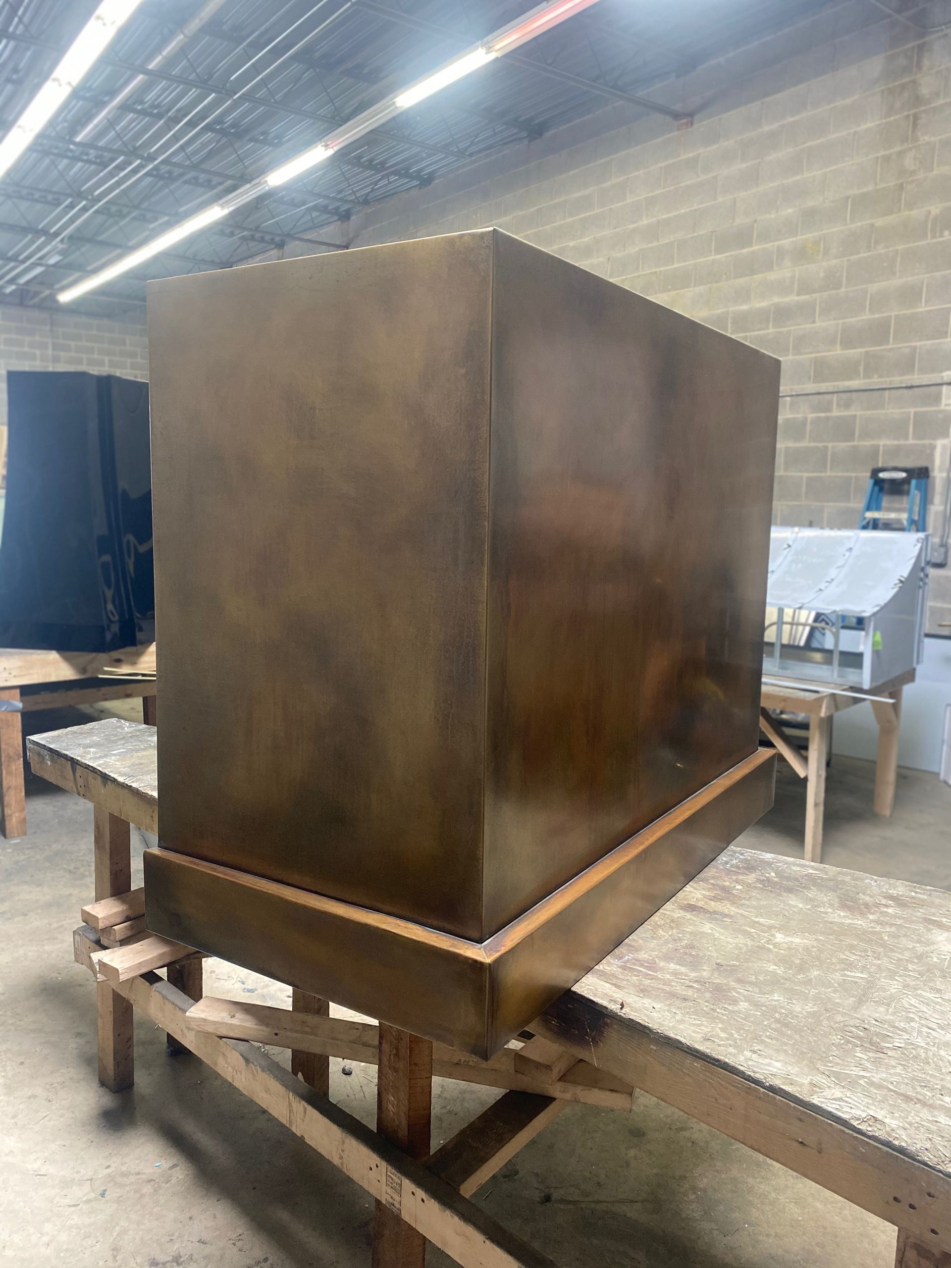 Large rust-colored metal box on a wooden work stand in an industrial workshop