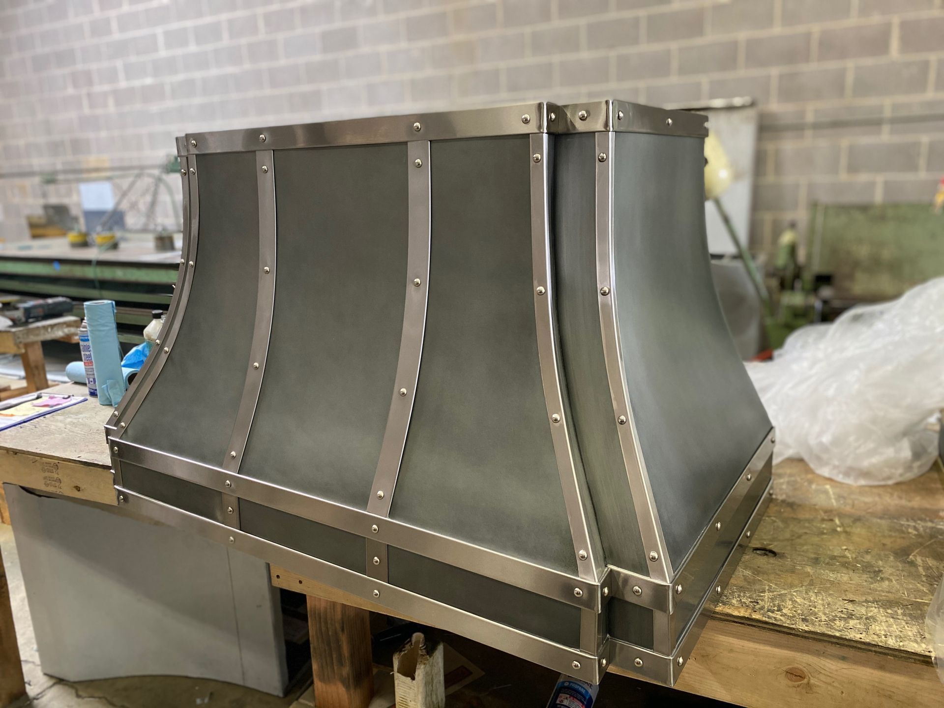 Metal hood or vent assembly with riveted panels on a workbench in a workshop