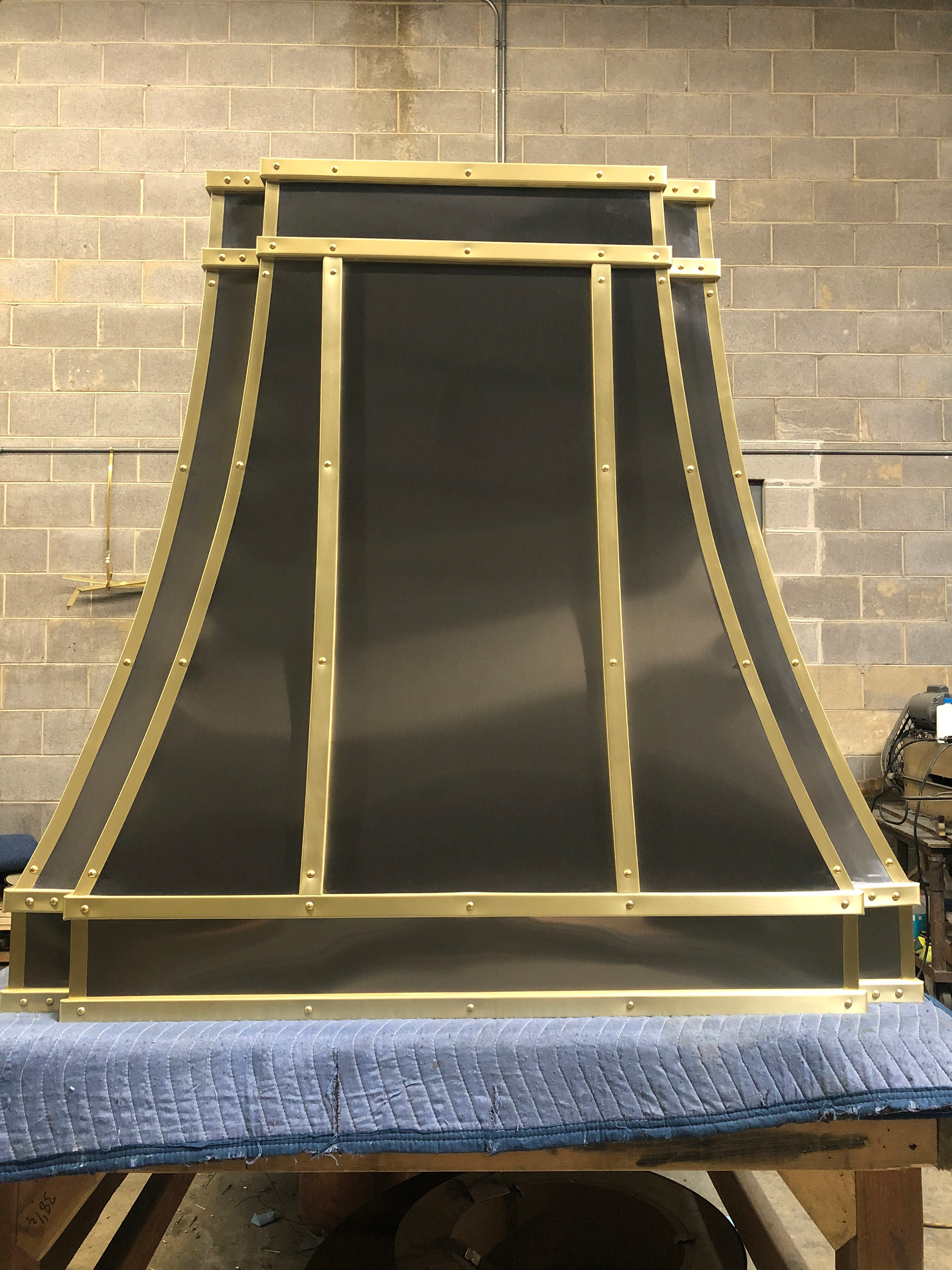 Black-and-gold speaker cabinet on a workbench against a brick wall