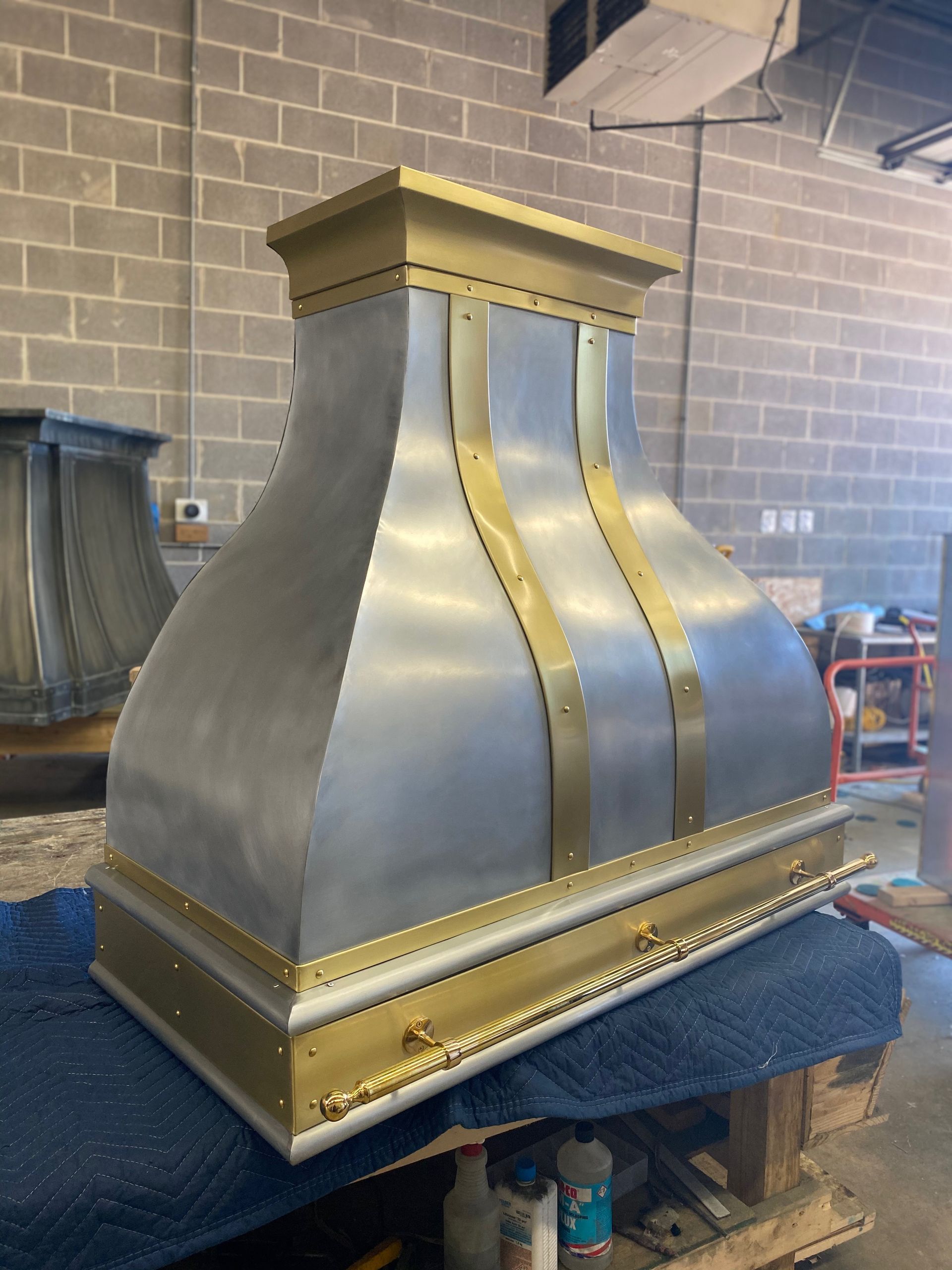 Metallic gold and silver industrial hood with curved sides on a workbench in a workshop