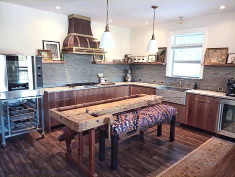 Cozy modern kitchen with wood cabinets, stone backsplash, and a rustic dining table in the foreground
