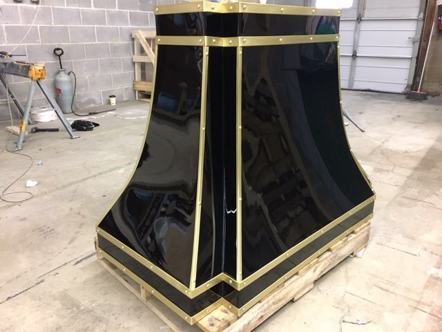 Black-and-gold decorative pedestal or cabinet on a wooden pallet in a workshop garage