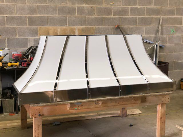 White metal roof panel on a wooden workbench in a workshop against a cinder block wall